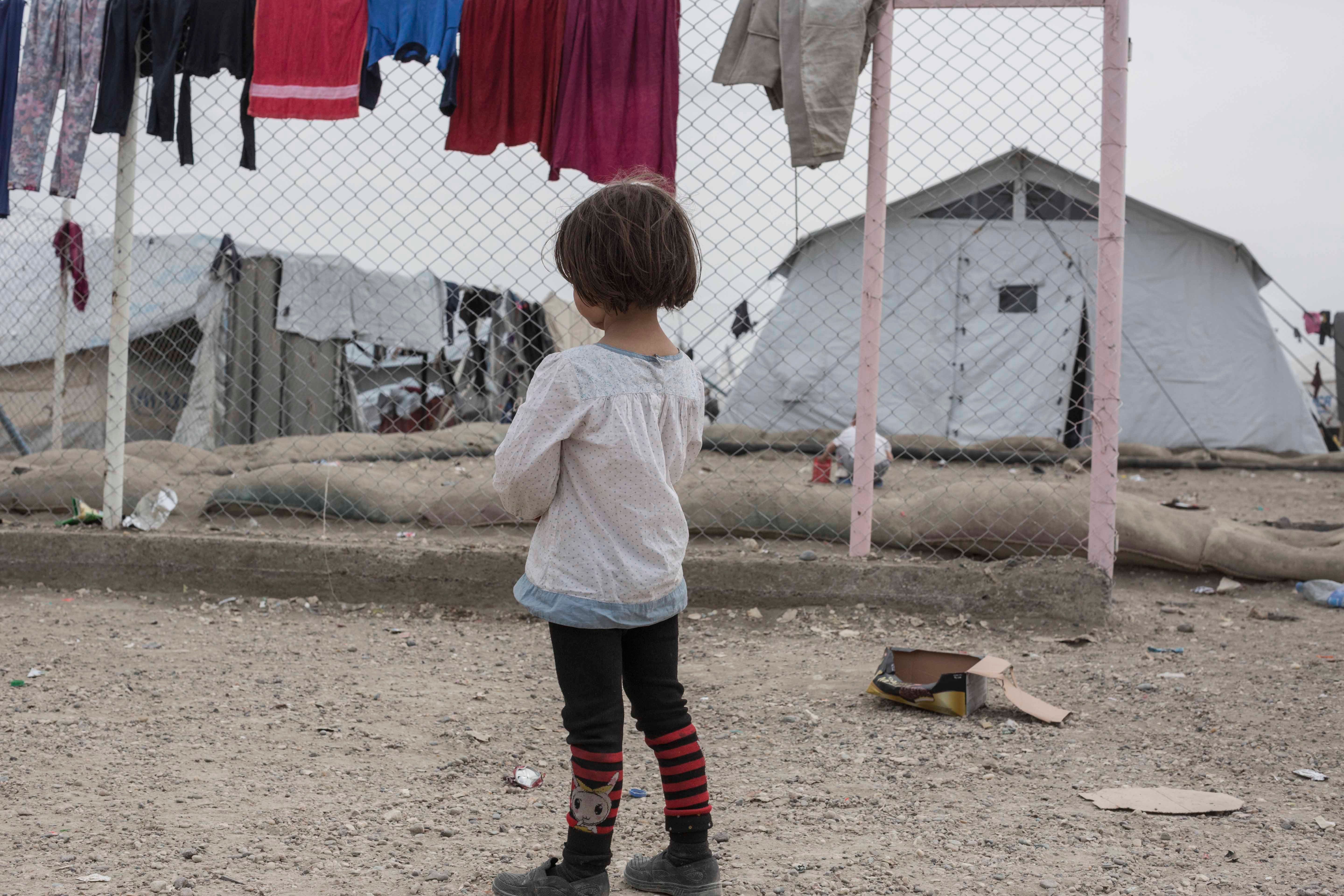 A girl stands near the fence