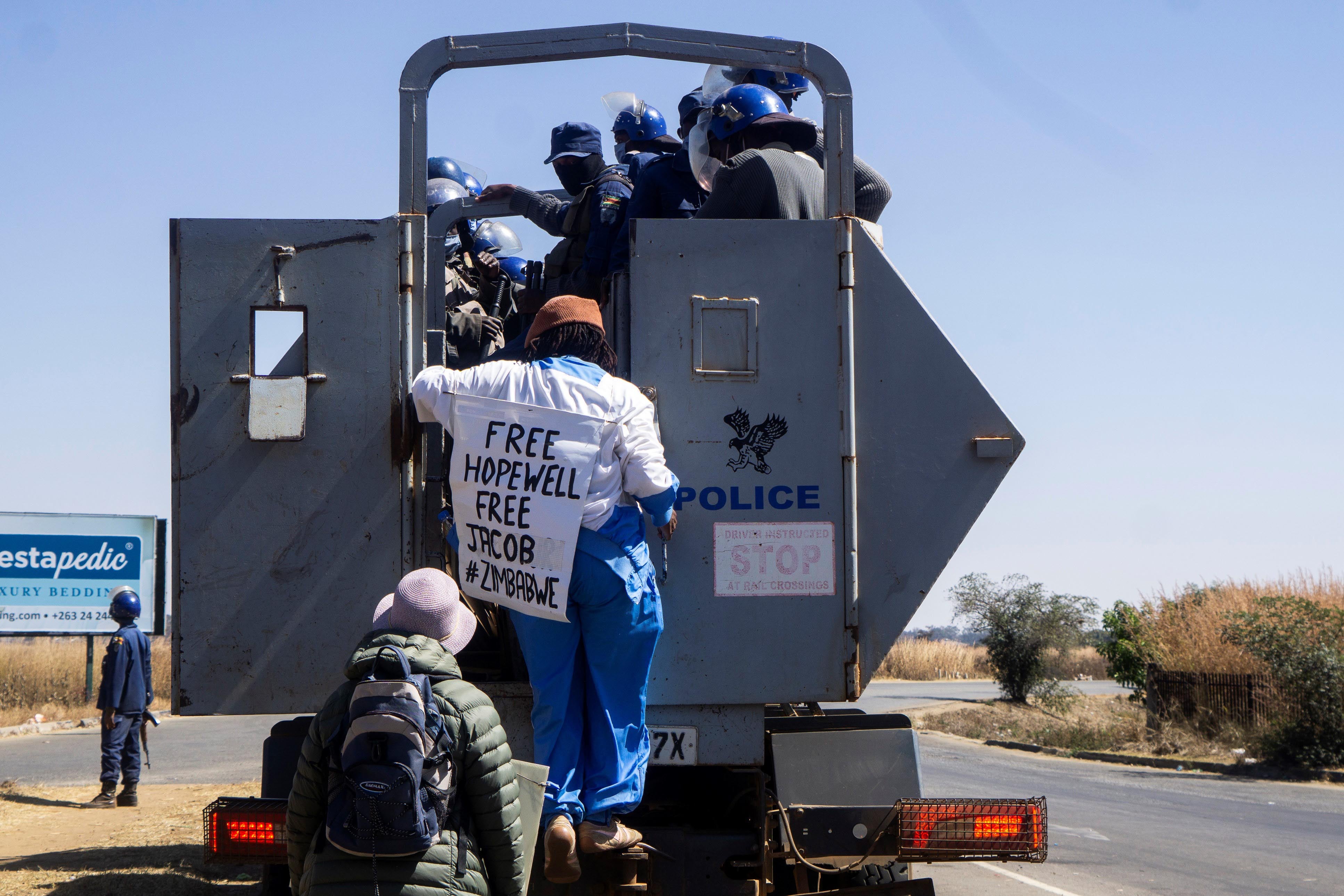 Zimbabwean novelist Tsitsi Dangarembga (center) and her colleague Julie Barnes hold placards as they are arrested during an anti-corruption protest march in Harare, Zimbabwe, on July 31, 2020.  © 2020 ZINYANGE AUNTONY / AFP