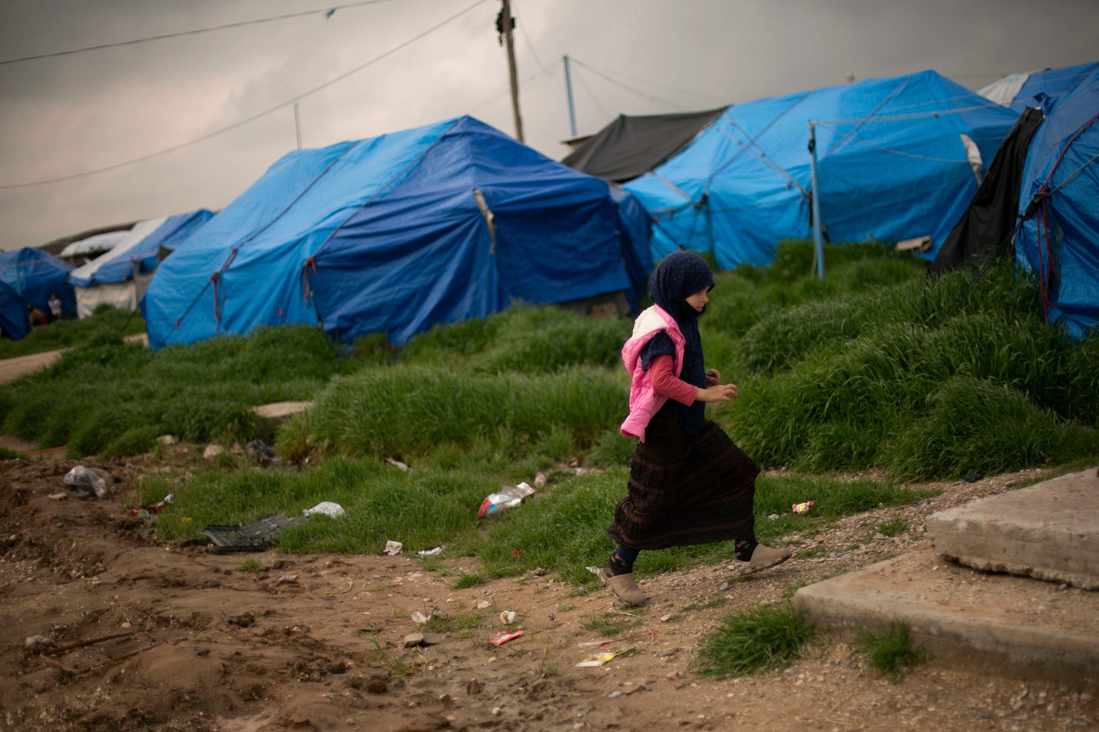 A girl walks through a tented area at Roj camp.