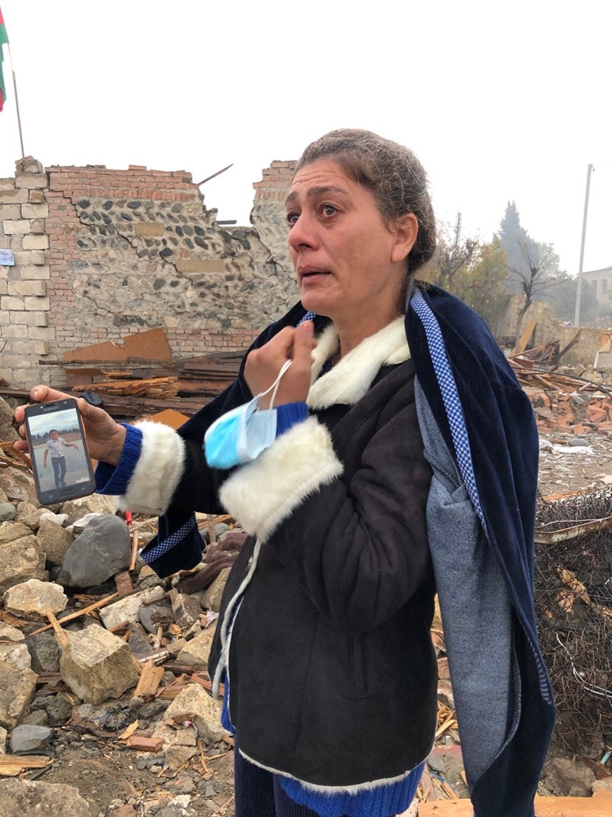 Qırx yeddi yaşlı Şairə Quliyeva dağıdılmış evinin önündə dayanıb 17 oktyabr tarixində ballistik raket zərbəsi nəticəsində həlak olmuş 13 yaşlı qardaşı oğlu Artur Quliyevin şəklini göstərir.