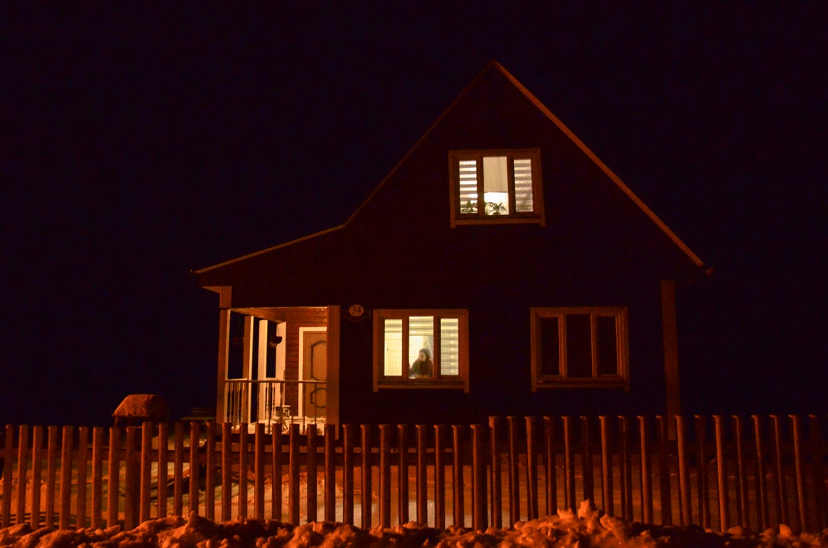 Юлия Ольшевская смотрит в окно своего дома под Минском, в котором она живёт вместе со своим мужем Сергеем, в настоящее время находящимся под стражей, январь 2021 года.