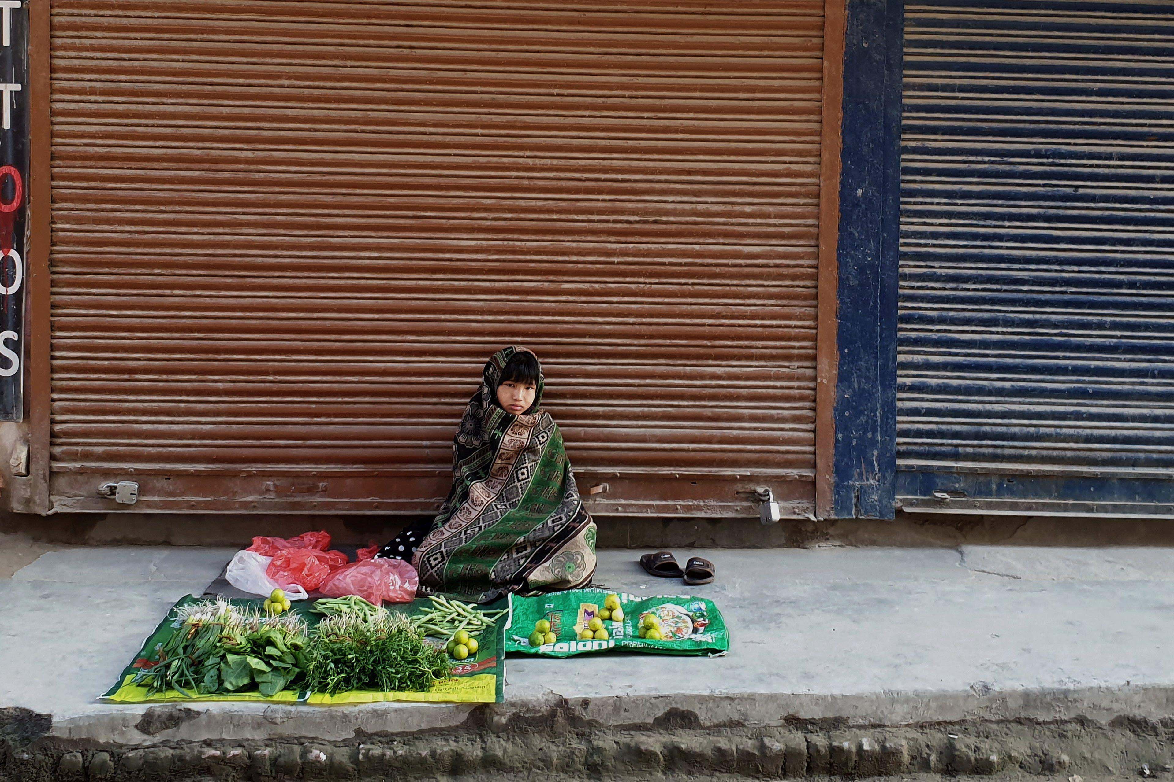 A child sits on the sidewalk in front of a display of goods to sell