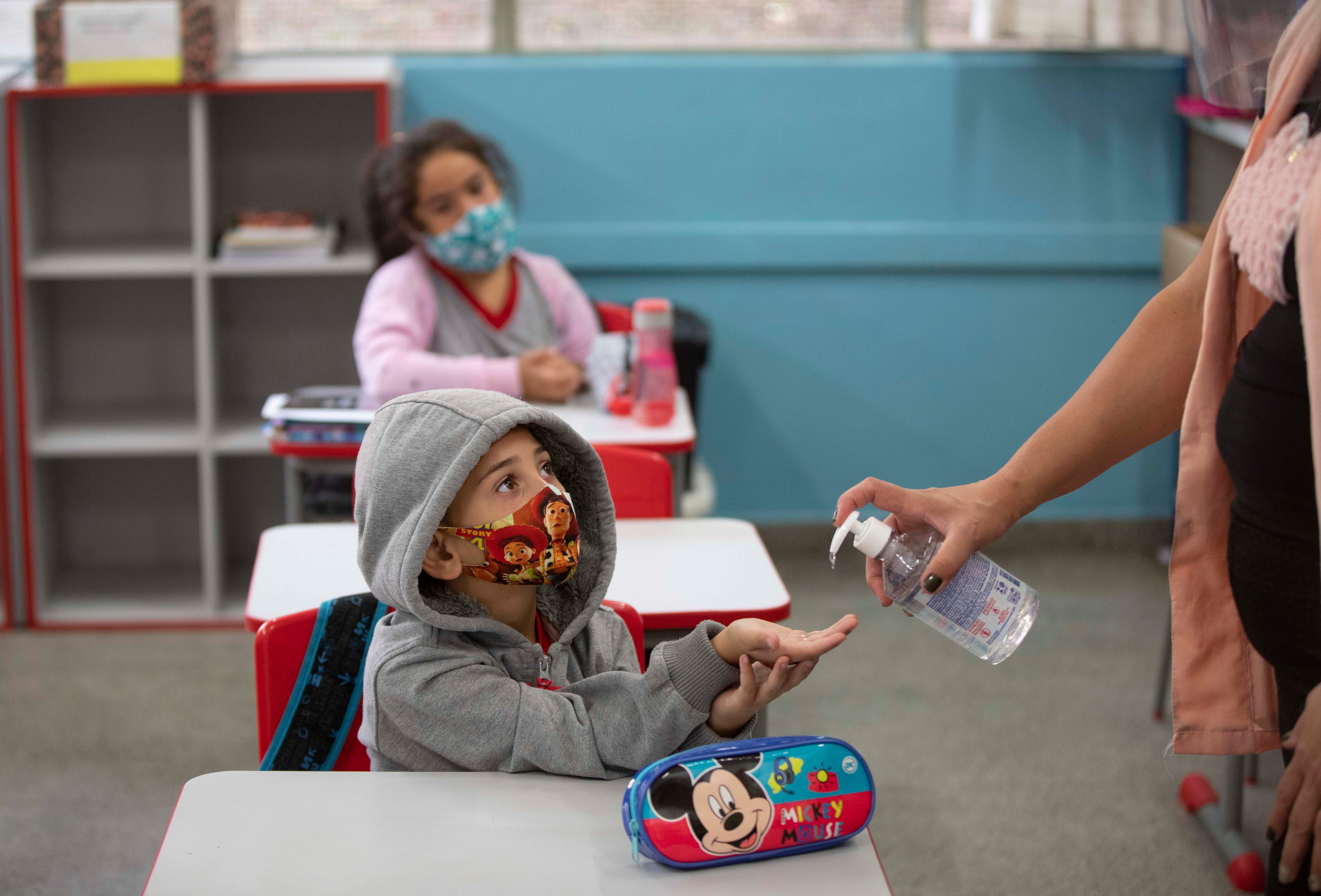 Um aluno recebe alcool em gel nas mãos em escola pública de São Paulo no primeiro dia de aula presencial, em 8 de fevereiro de 2021.