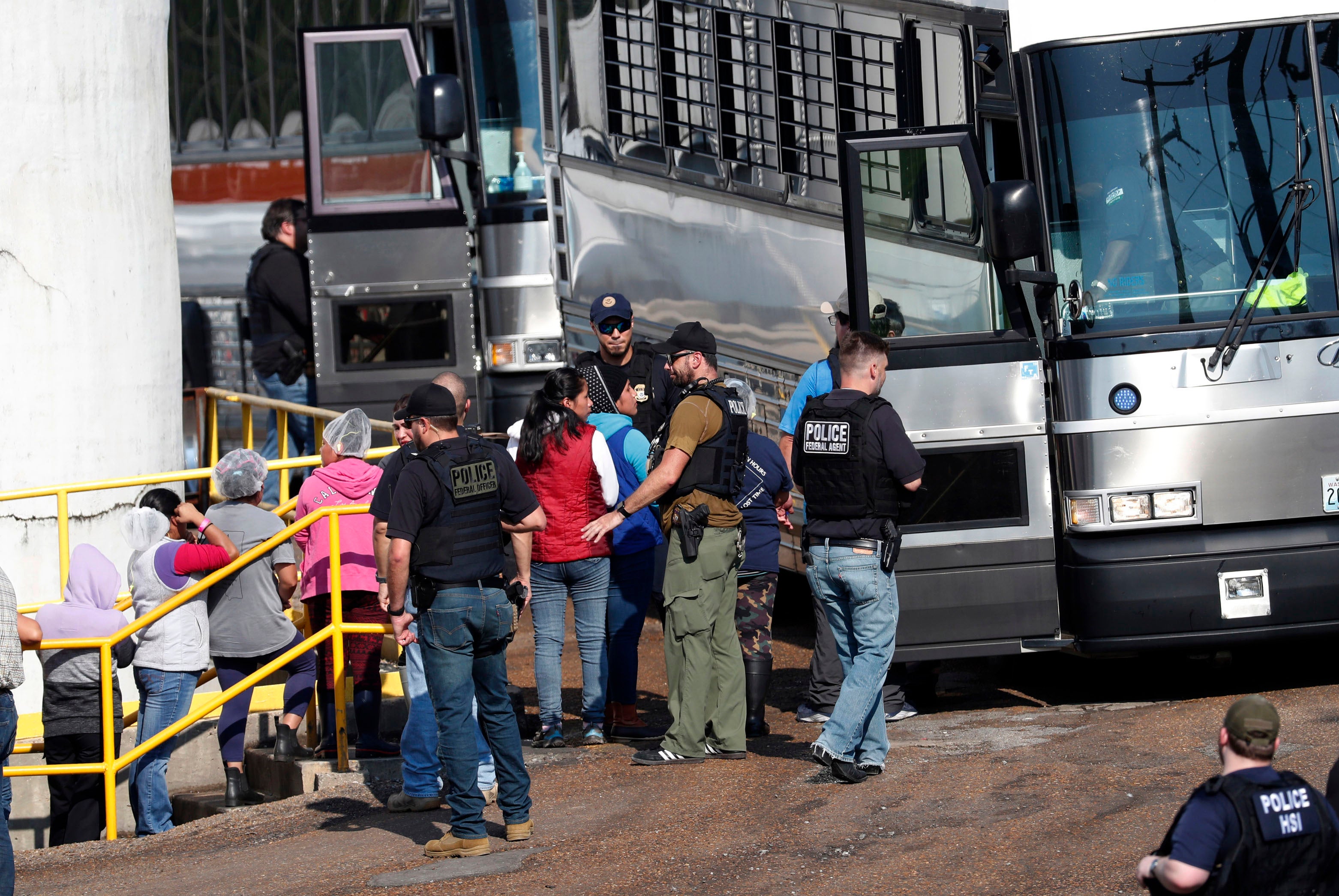 Uniformed police officers put people on a bus