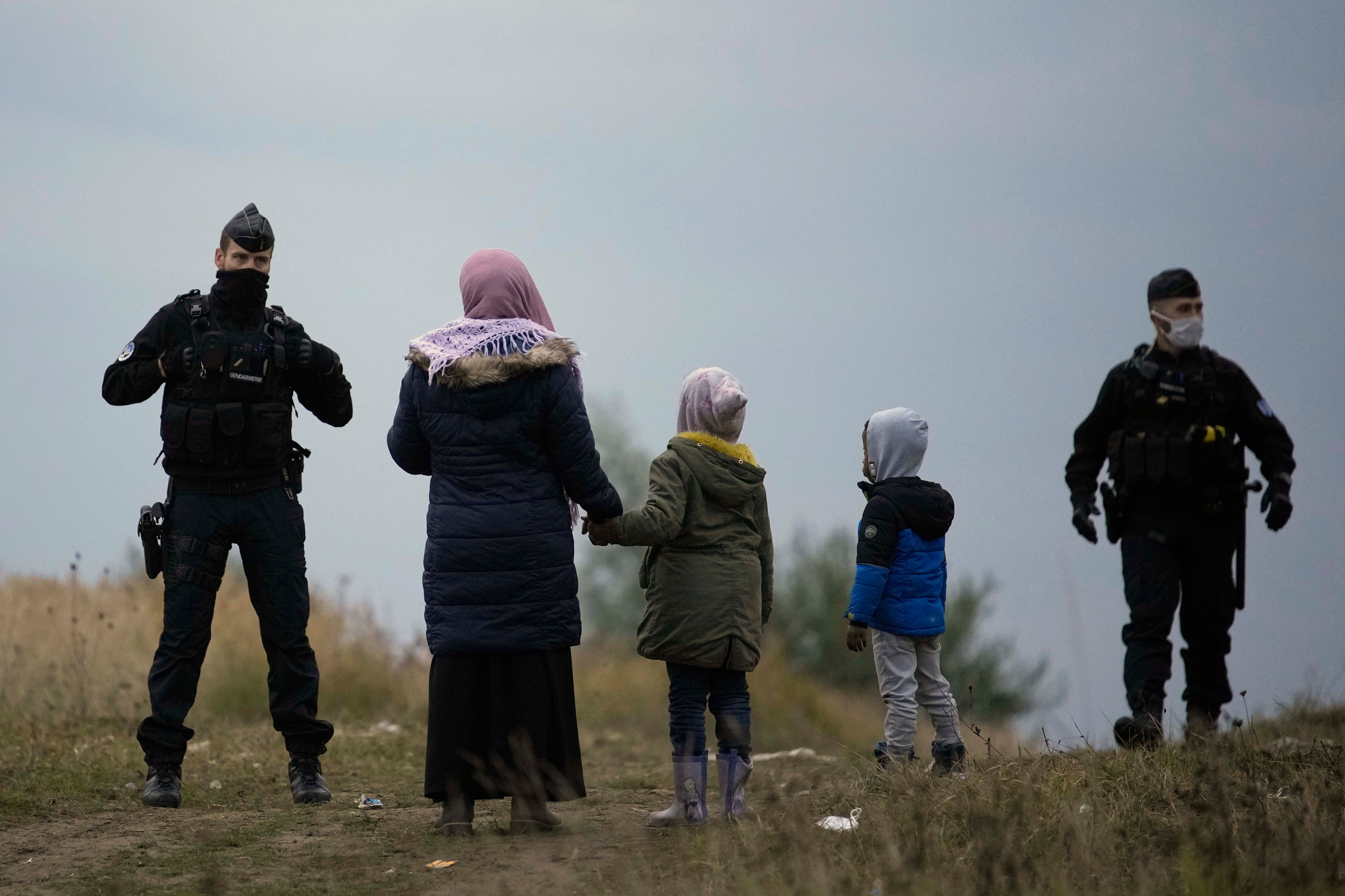 A woman and two children stand in front of two police officers