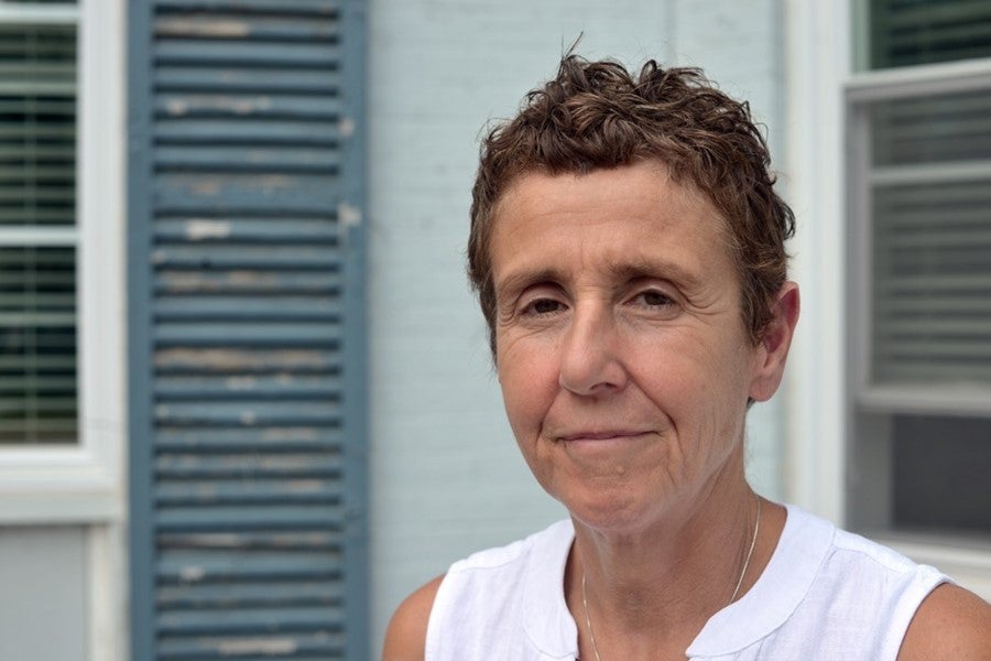 A woman stands outside during the day looking at the camera