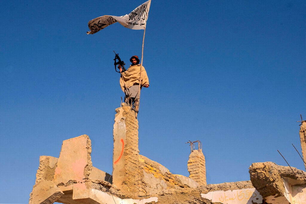 A Taliban fighter raises a flag in the ruins of Sangin, Helmand province, Afghanistan, November 30, 2021.