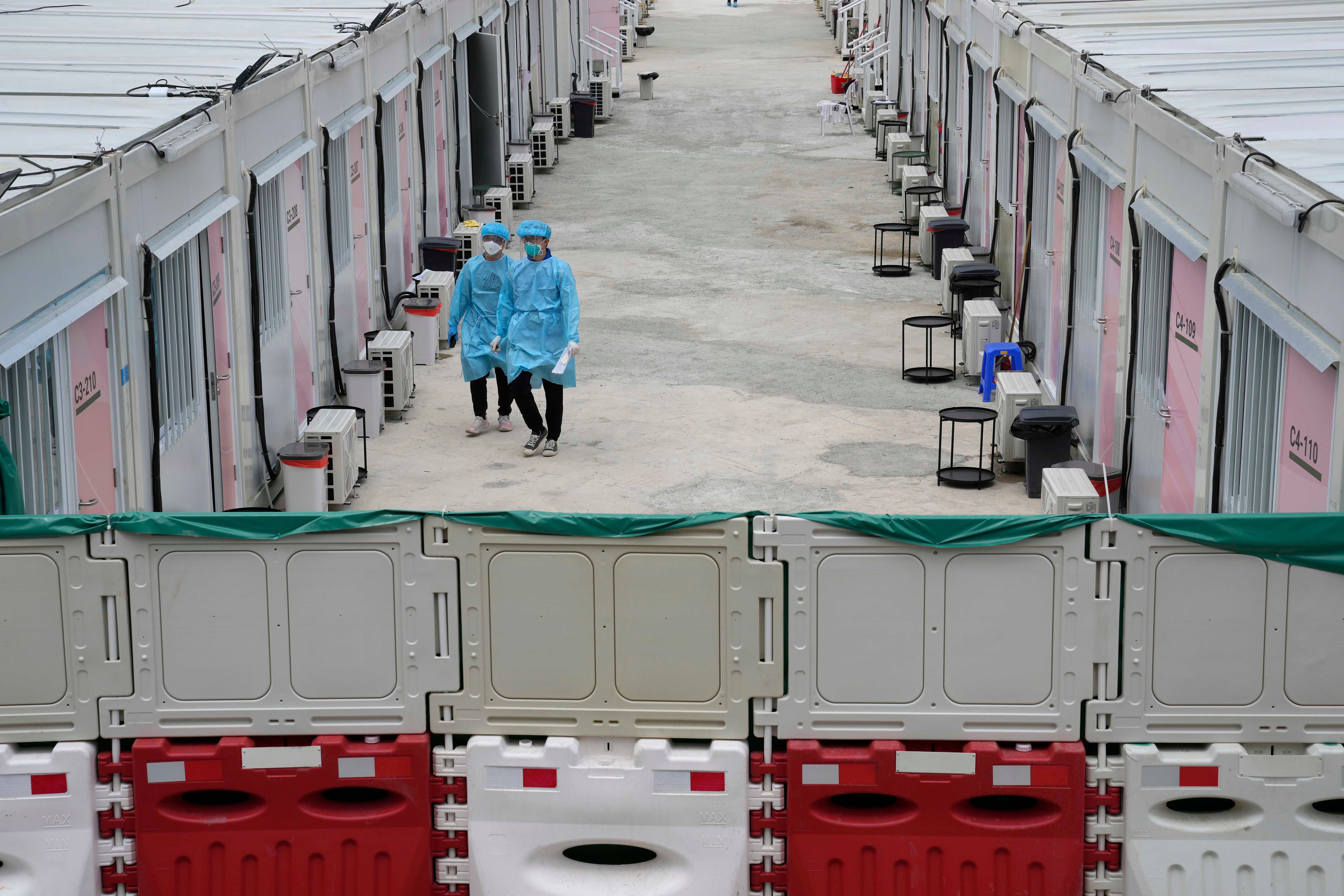 Healthcare workers walk along the makeshift Covid-19 isolation facilities in the San Tin area of Hong Kong, March 11, 2022. 