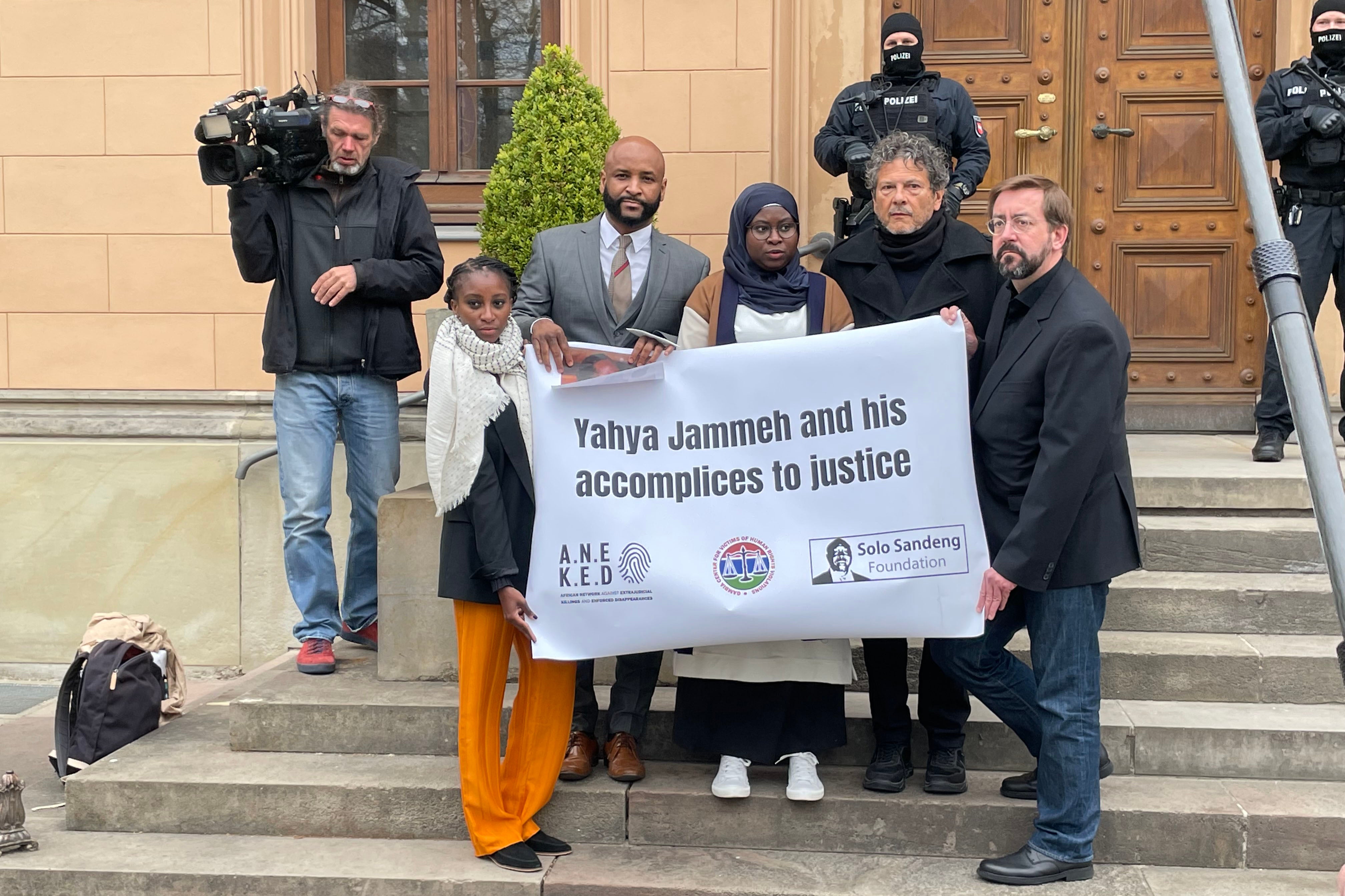 A group of people standing on steps hold a sign