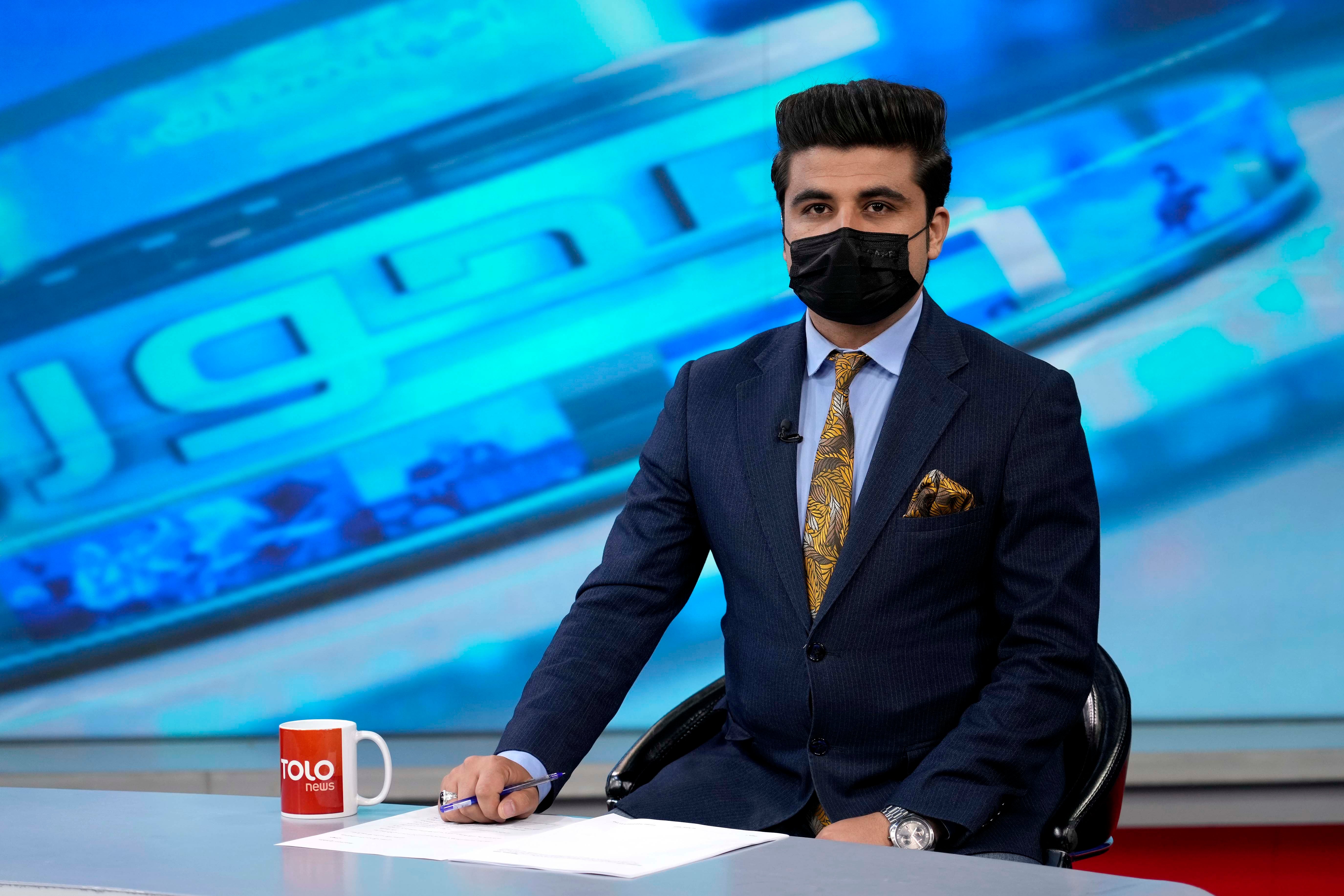 Nesar Nabil, présentateur de la chaîne de télévision afghane ToloNews, portait un masque facial noir en guise de solidarité avec ses consœurs, lors de la diffusion du journal télévisé enregistré dans le studio de la chaîne à Kaboul, le 22 mai 2022. Un récent décret des talibans exige que les présentatrices se couvrent le visage.