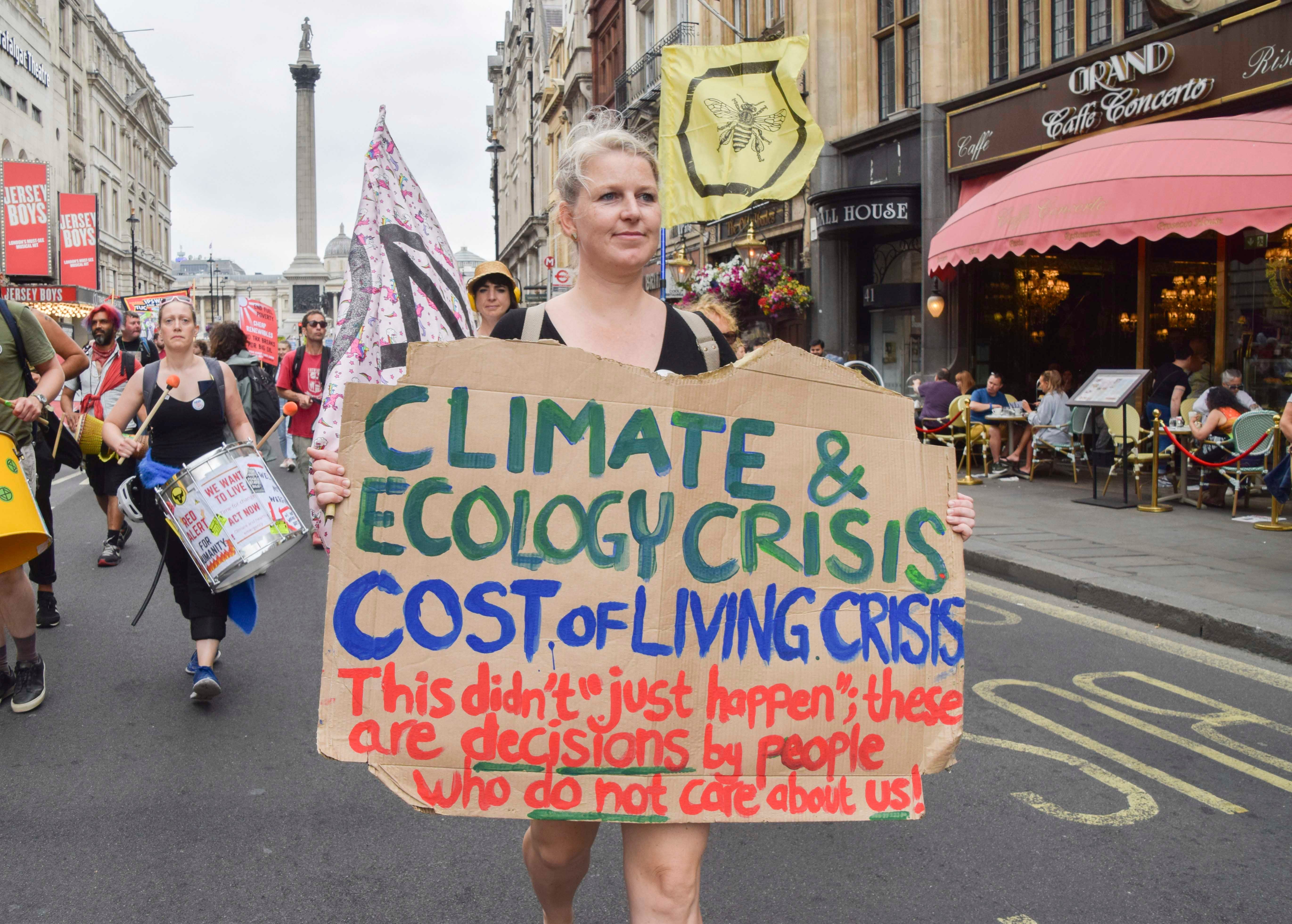 A protester holds a placard linking the climate crisis with the cost of living crisis