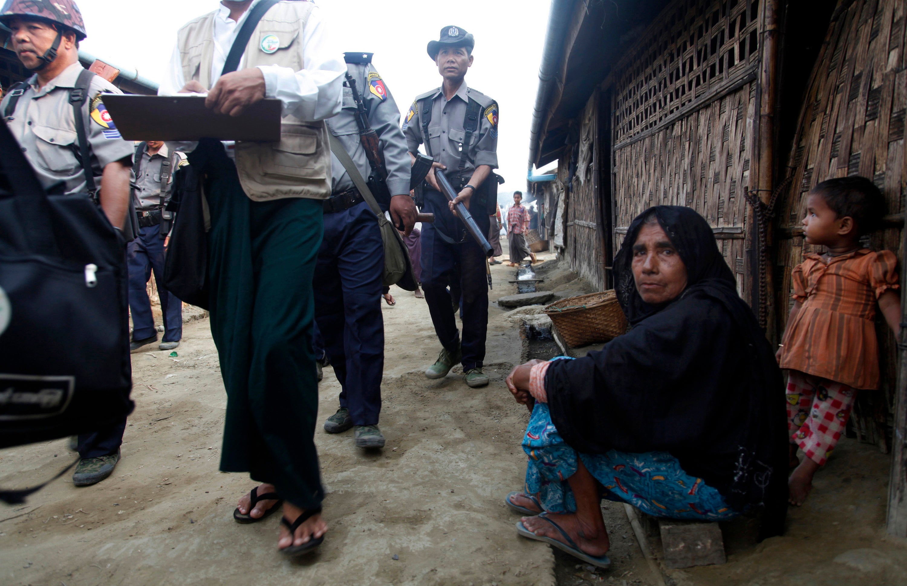 A woman and child watch census workers walk past