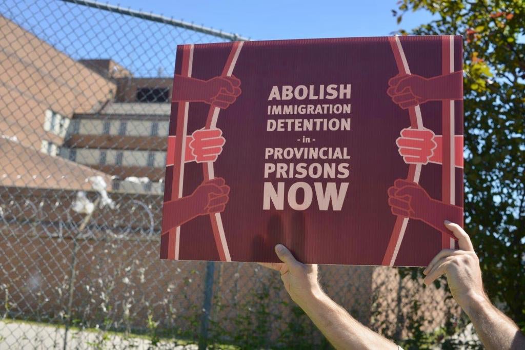 A protestor holds a sign outside a provincial jail in Toronto.