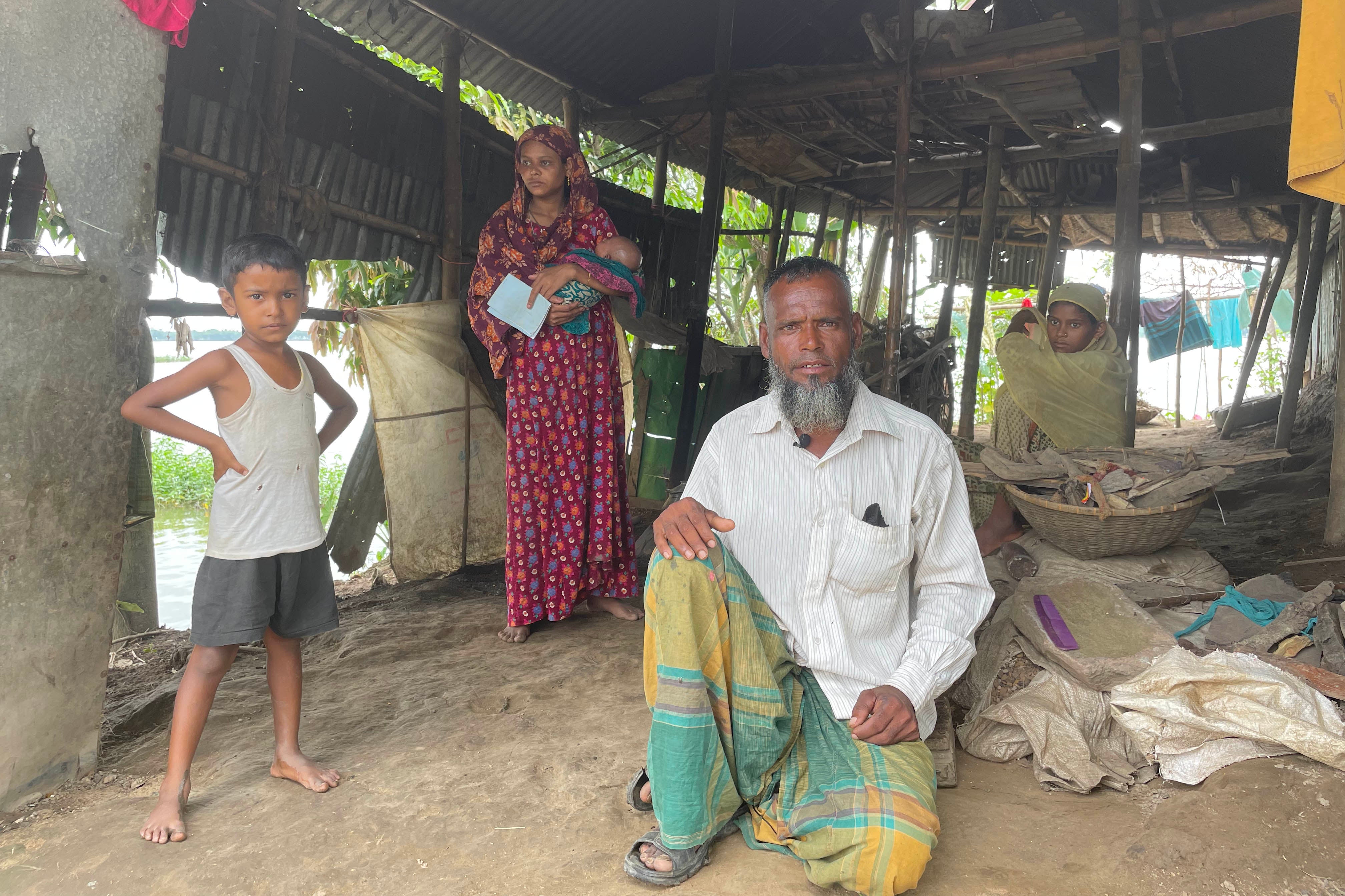 A man sits next to his daughter and grandchildren in their house