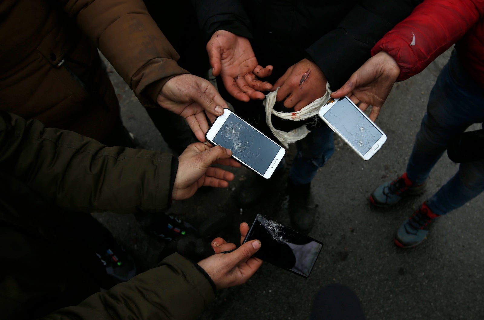 Migrants show broken phones in the village of Horgos, Serbia