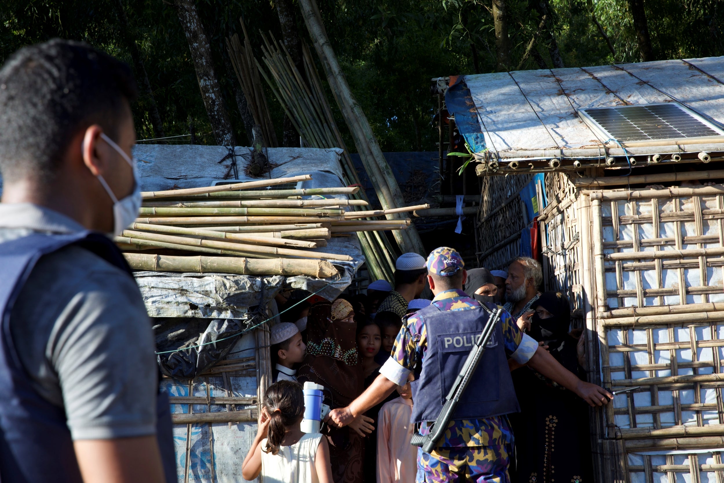 Police officers stand guard in front of Rohingya refugees at Kutupalong camp in Cox’s Bazar, Bangladesh, September 30, 2021.