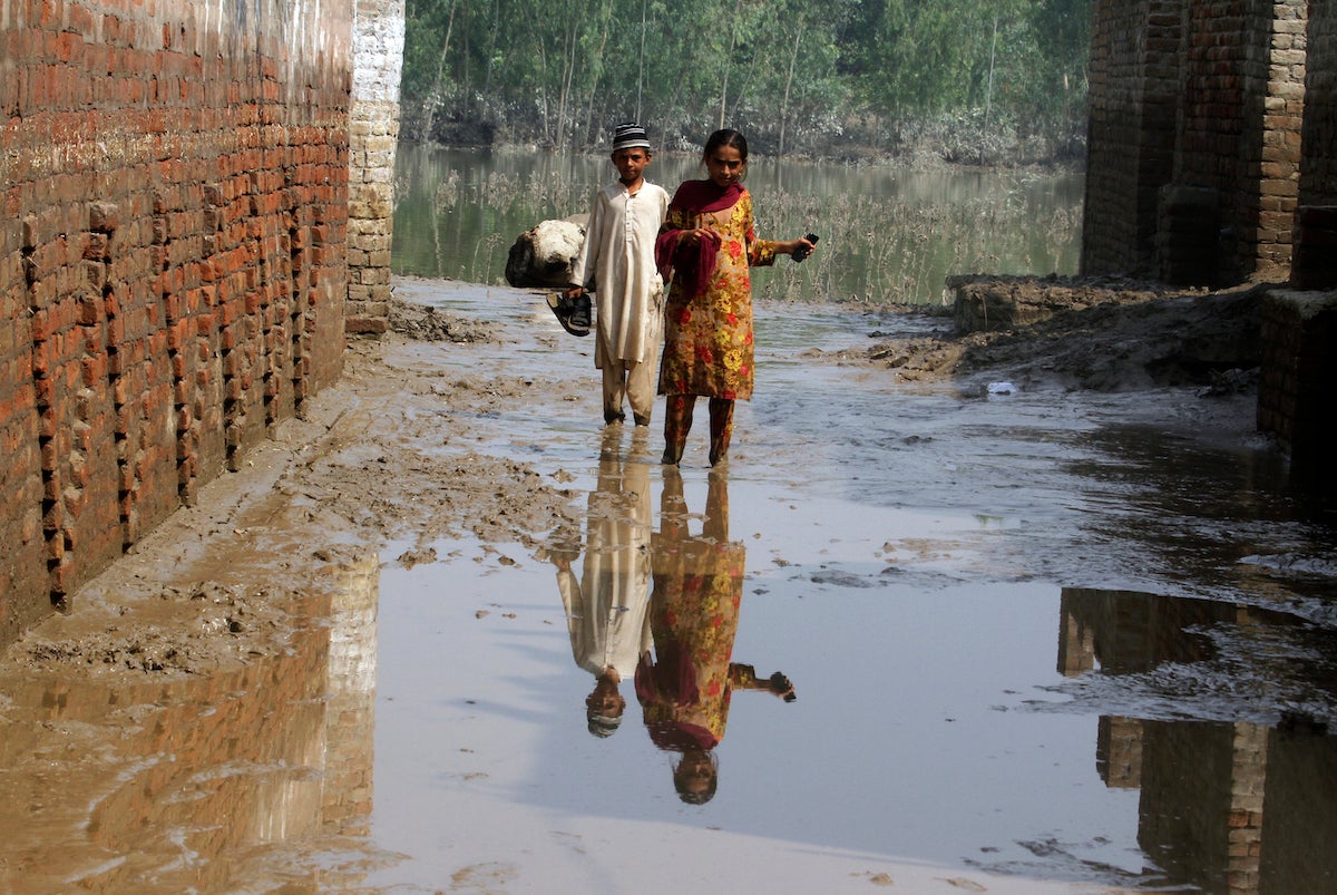 Two children wade through mud near their flood-hit home in Charsadda, Pakistan.