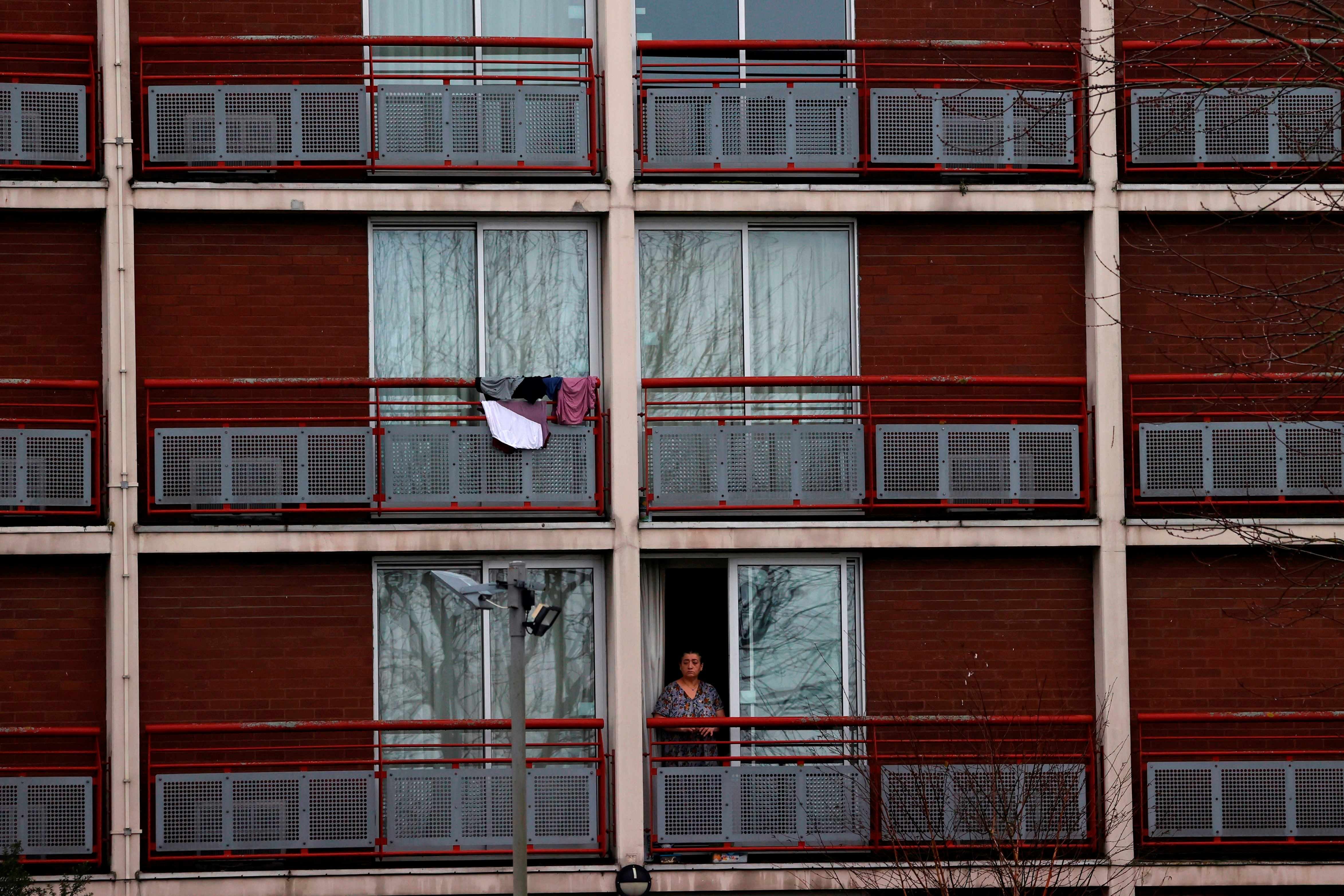A woman stands in the doorway of an apartment block 
