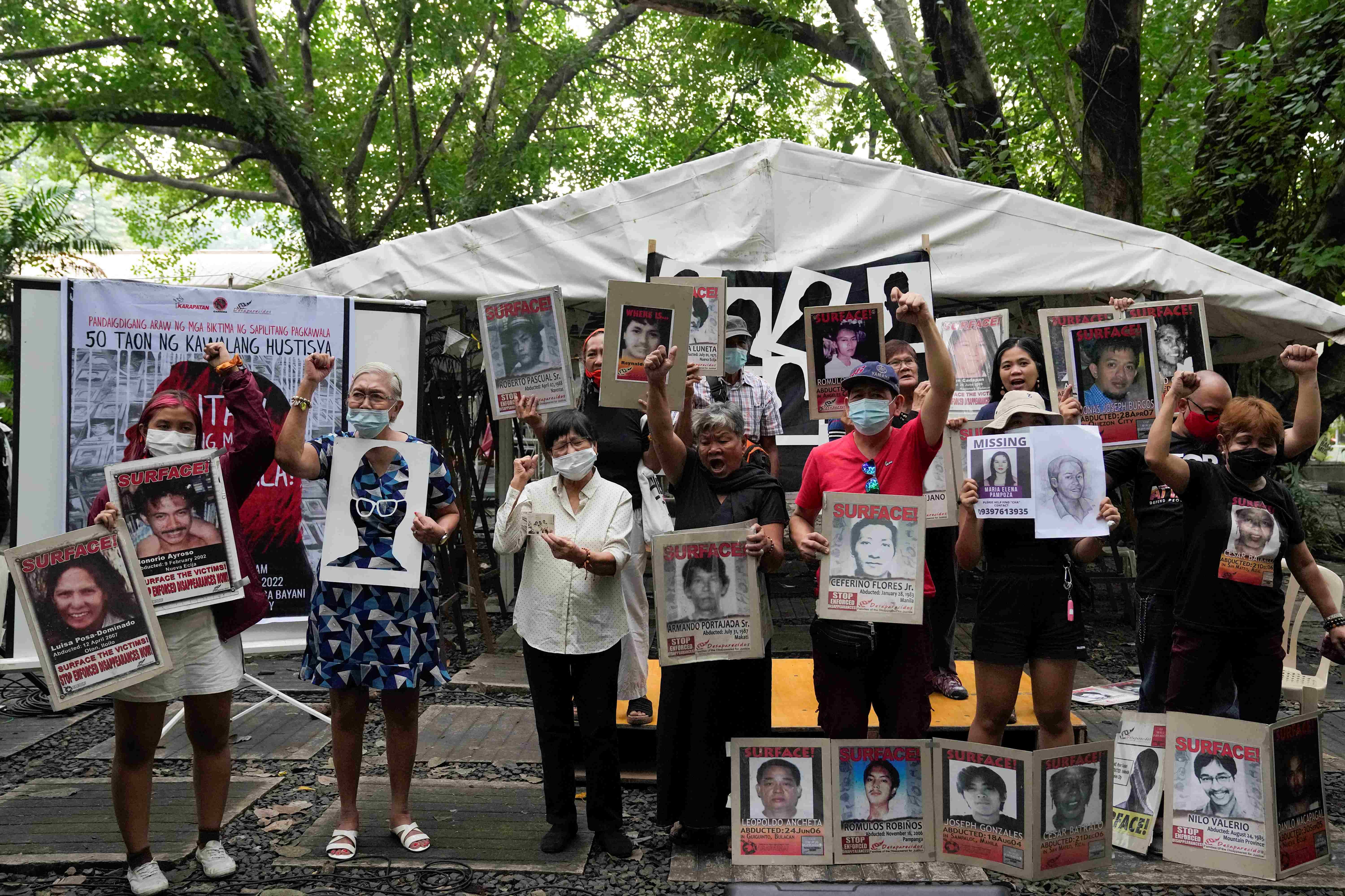 A group of people hold placards and shout slogans at a protest