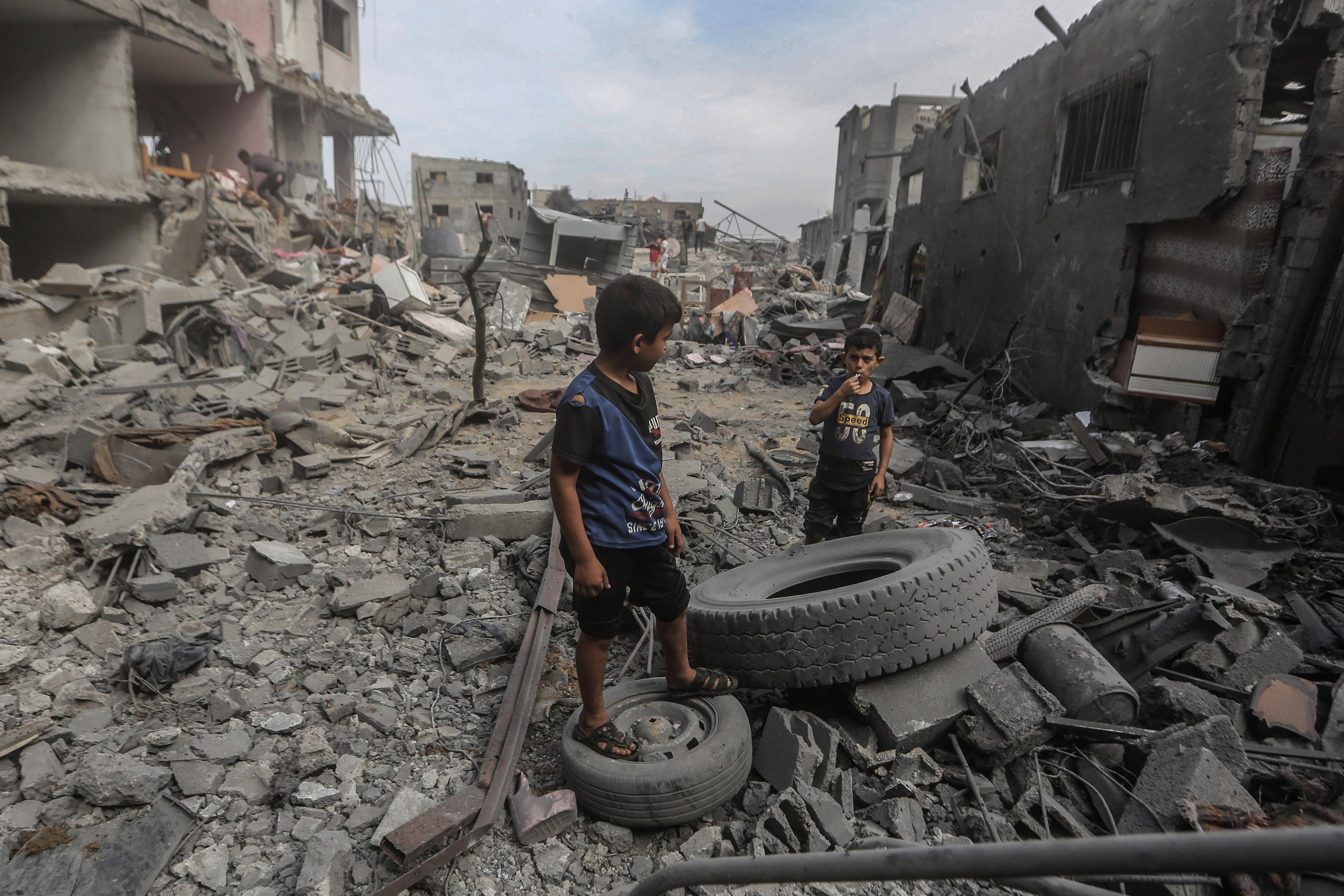 Palestinian children stand amid the rubble of destroyed buildings in Al-Bureij camp, Gaza