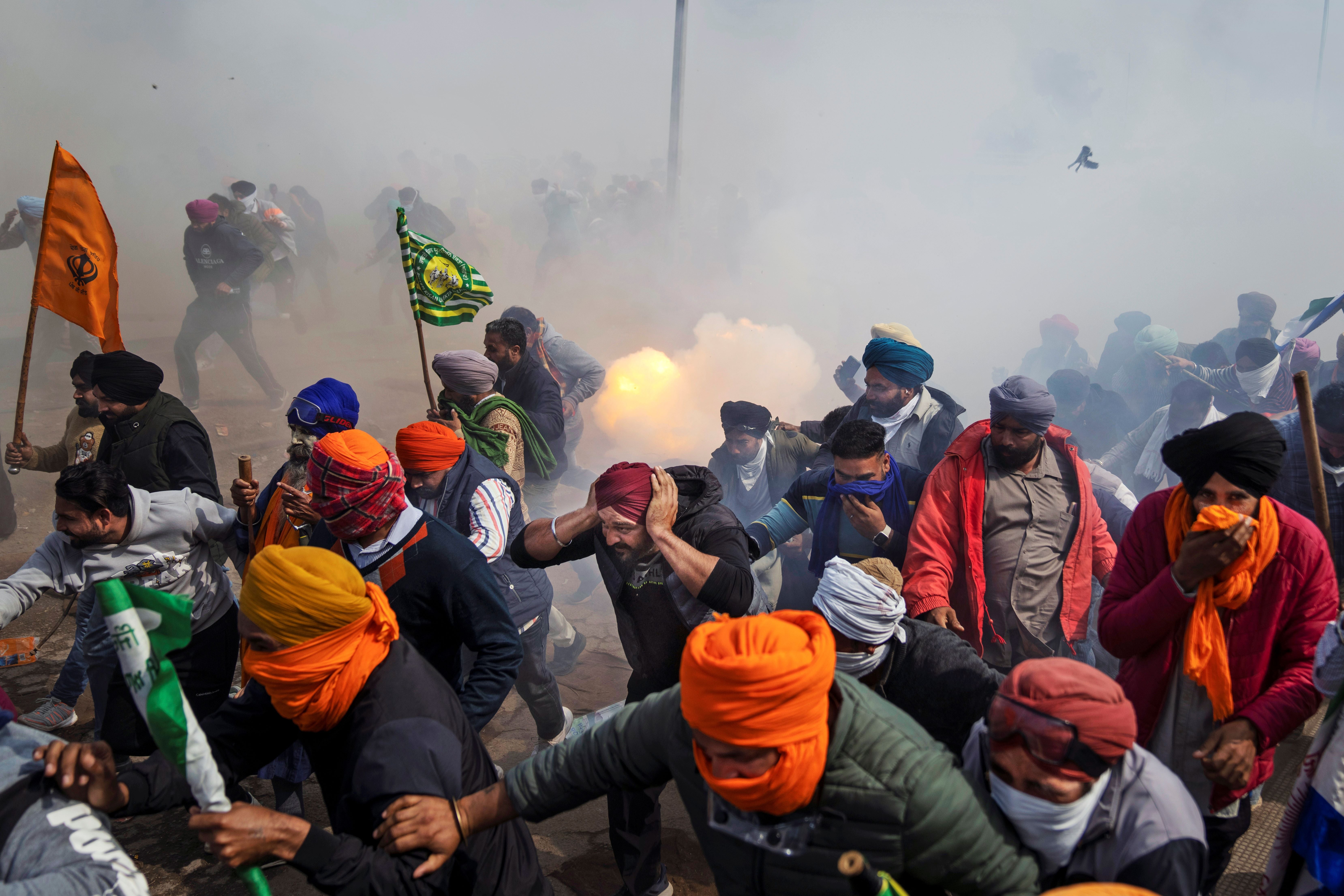 Protesting farmers flee exploding tear gas shells.
