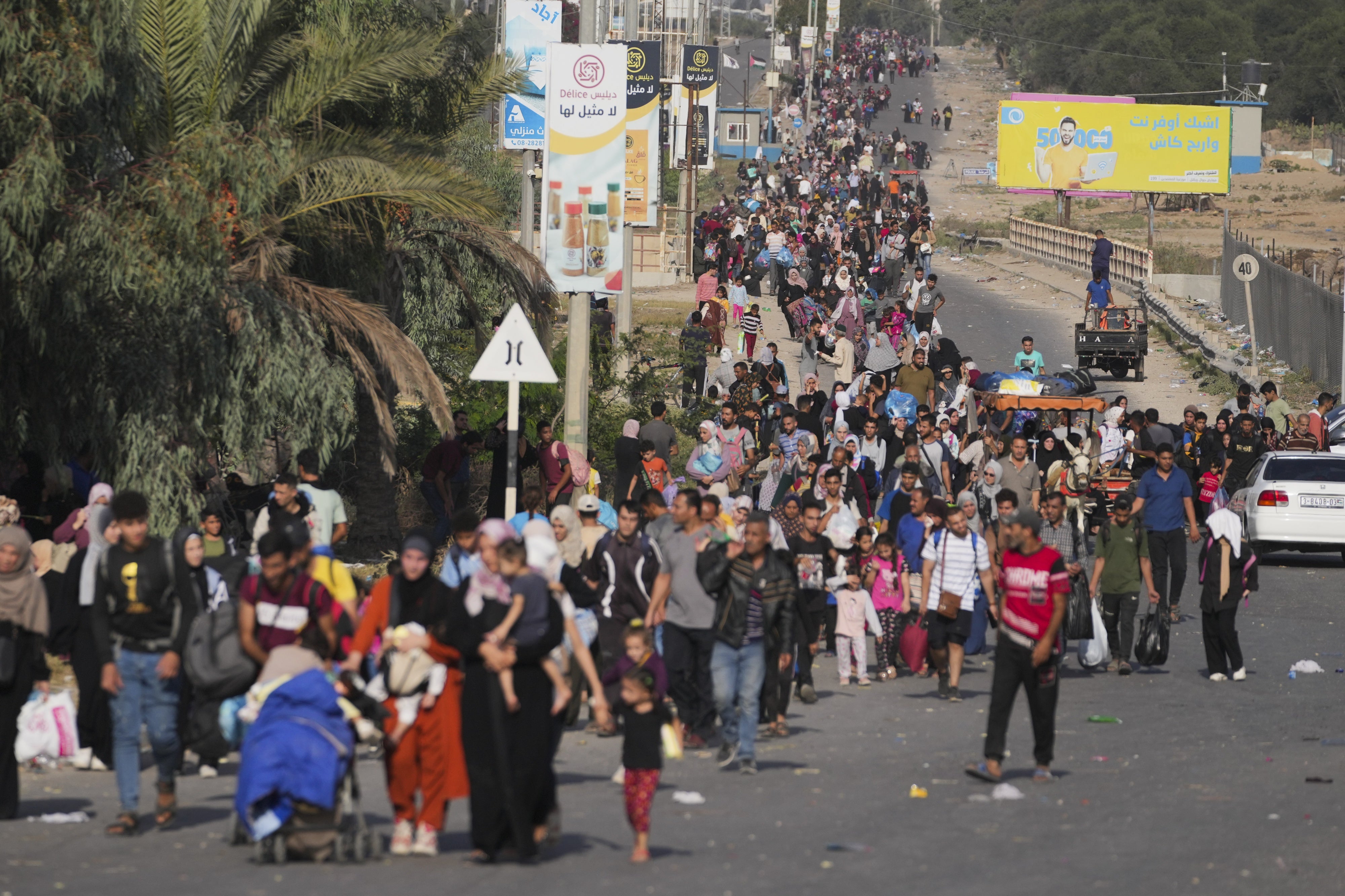 Large groups of people fleeing with their possessions on a main road