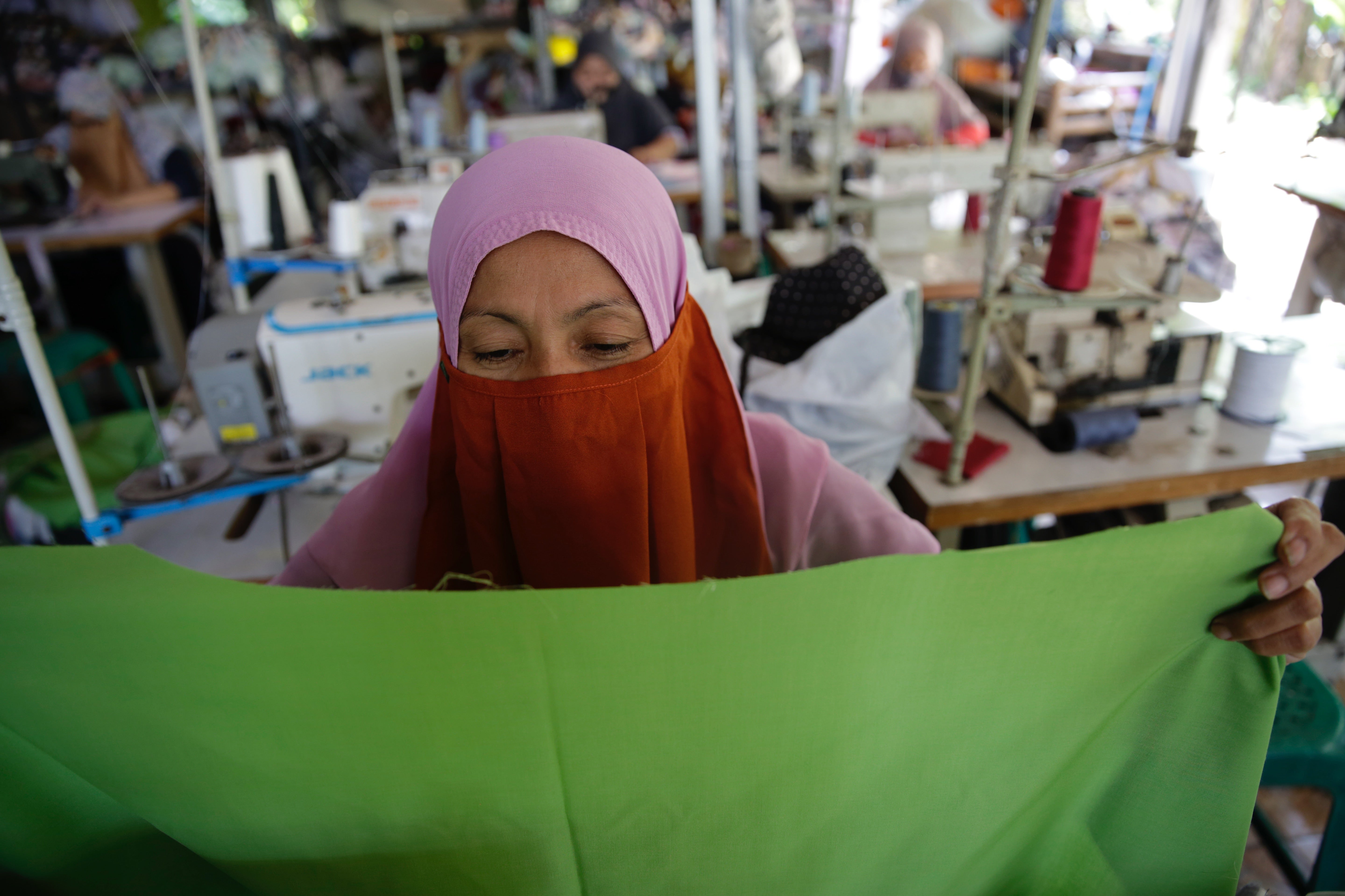 A worker sews a garment at a home-based apparel production operation in Bogor, Indonesia, March 4, 2021.