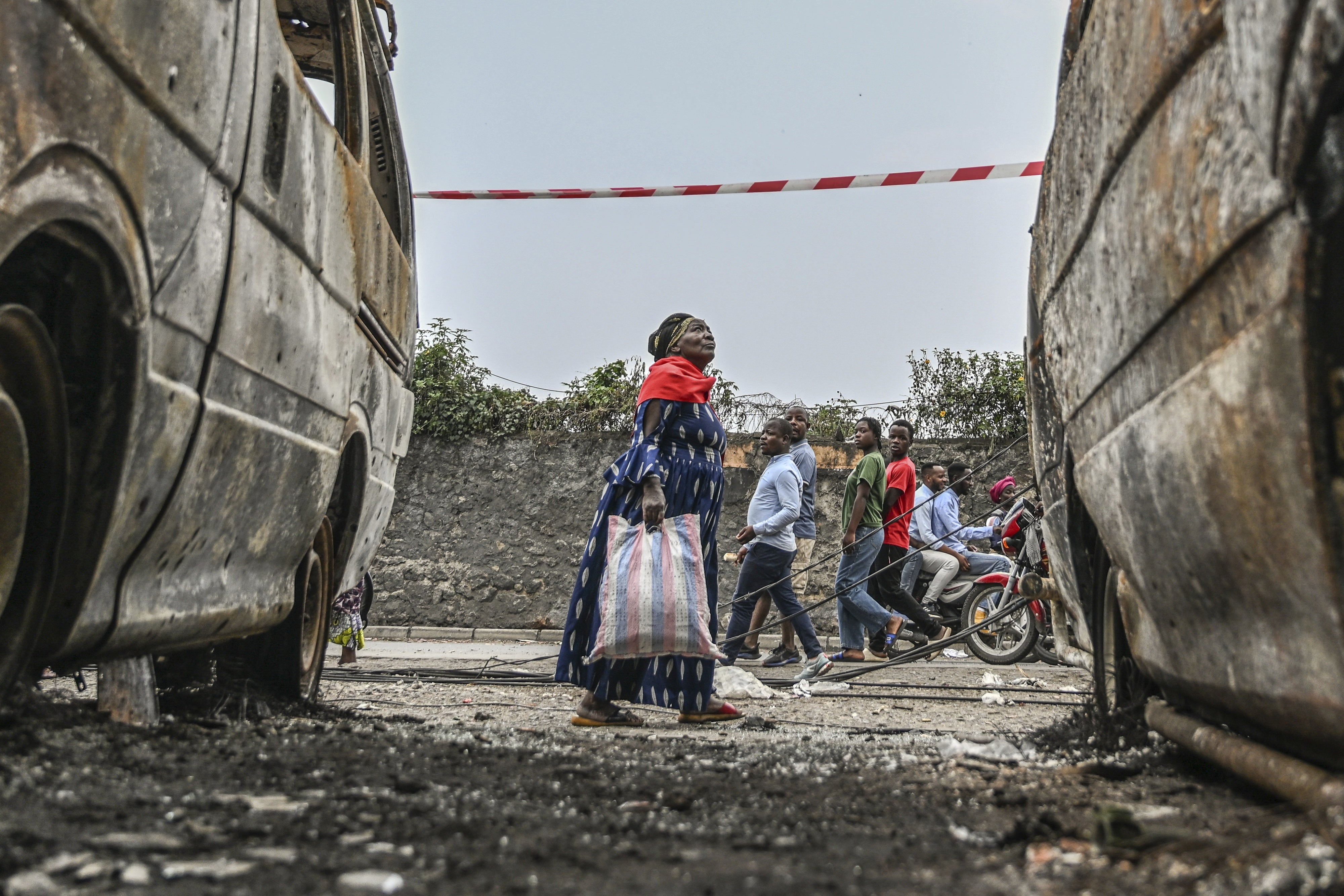 Residents walk by charred vehicles in Goma, Democratic Republic of Congo, January 31, 2025.