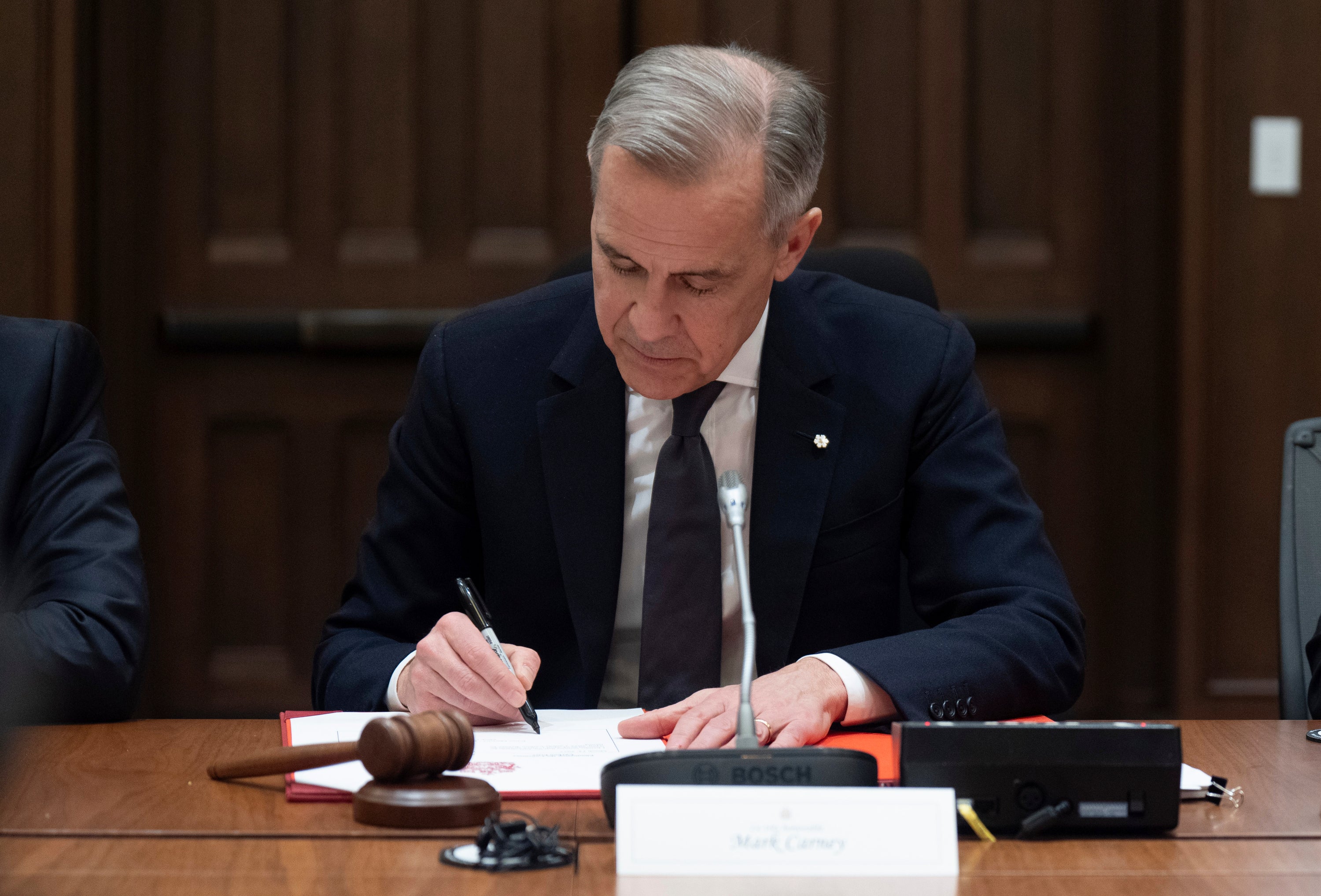 Canadian Prime Minister Mark Carney signs a document during cabinet meeting on Parliament Hill in Ottawa., March 14, 2025.