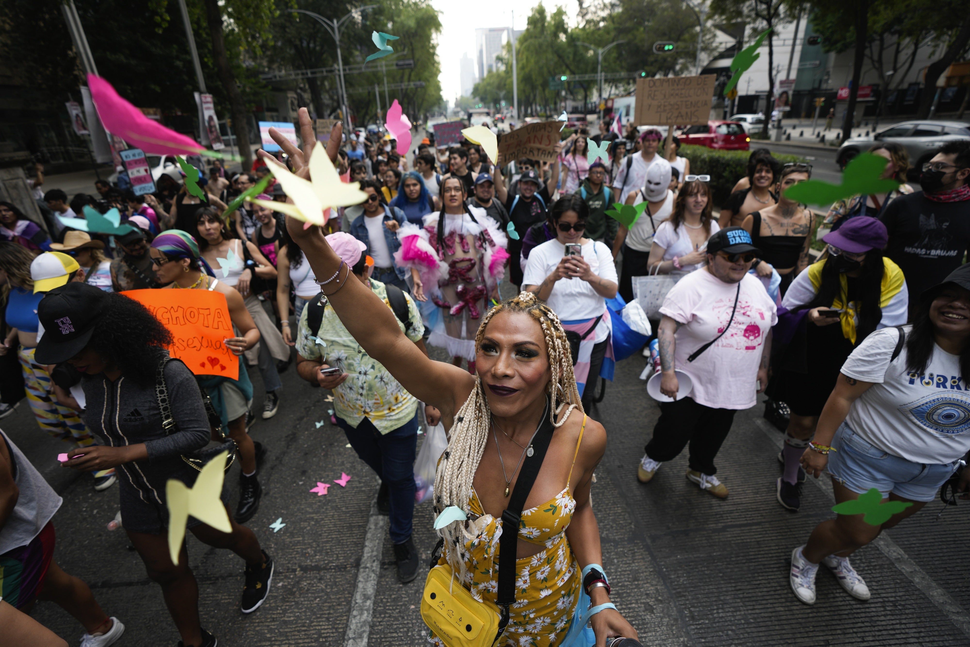 Una persona manifestante lanza papeles de colores con forma de mariposas durante una protesta para exigir una ley que proteja los derechos de la comunidad trans frente al edificio del Congreso en la Ciudad de México, el 31 de marzo de 2024.