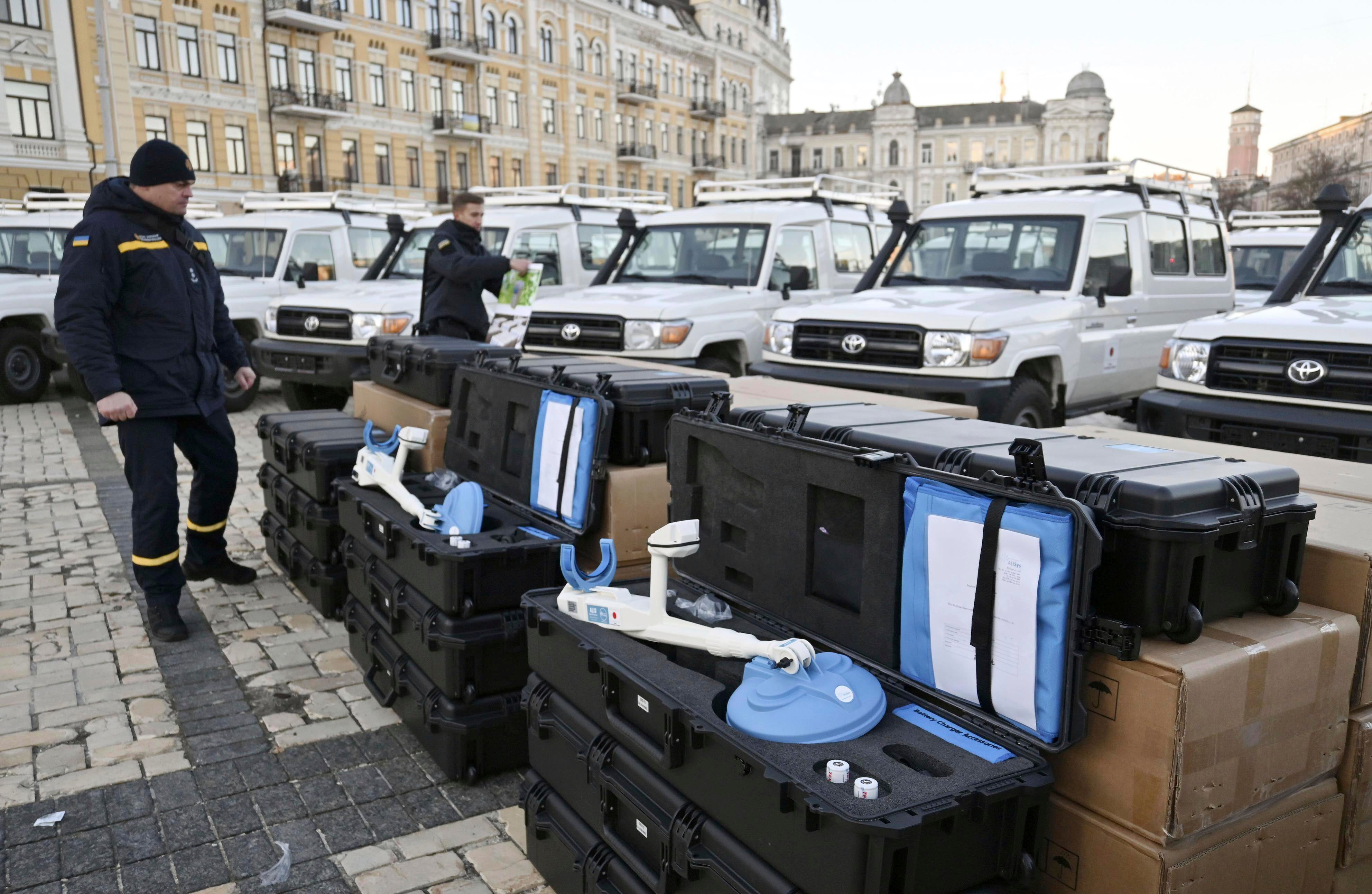 Two men stand by metal detectors used for demining.  