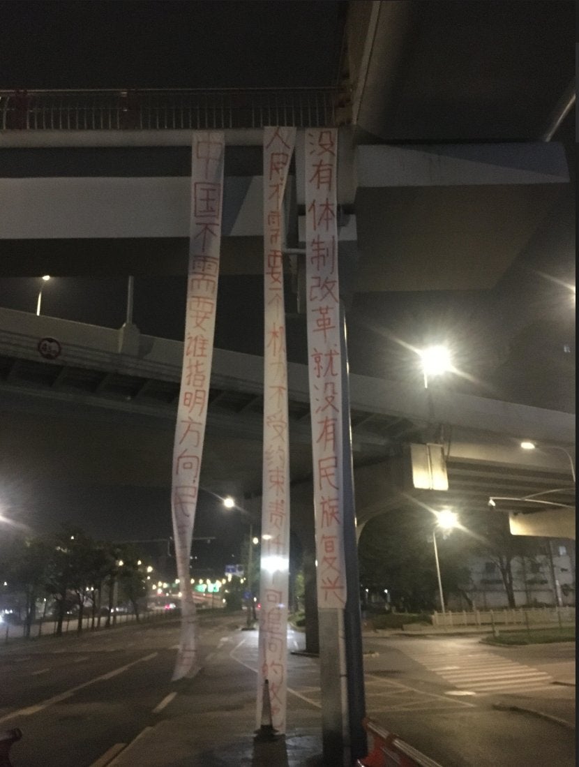 Three pro-democracy banners hang from an overpass outside the Chengdu Chadianzi Station in China’s Sichuan province on the morning of April 15, 2025.
