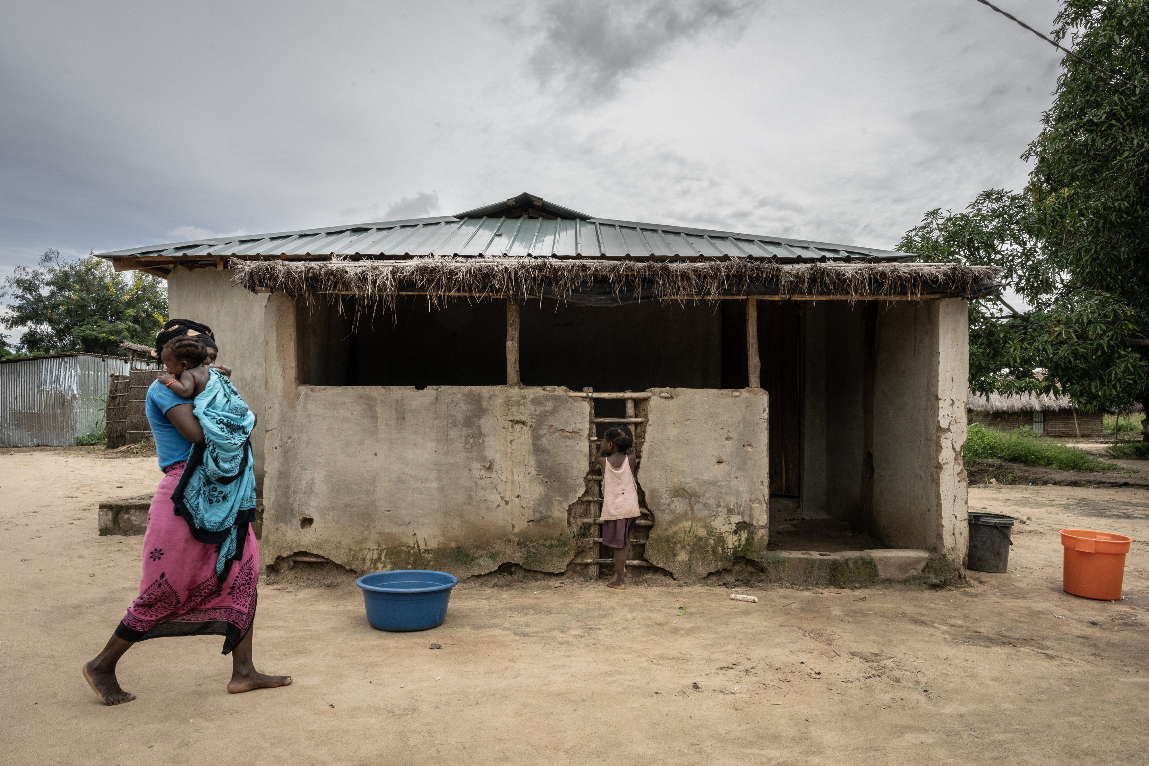 Une jeune femme mozambicaine portait l’une de ses filles, tandis que son autre fille s’arrêtait devant une structure de la communauté de Saul, dans la région de Metuge située dans la province de Cabo Delgado, au Mozambique, le 26 mars 2024.