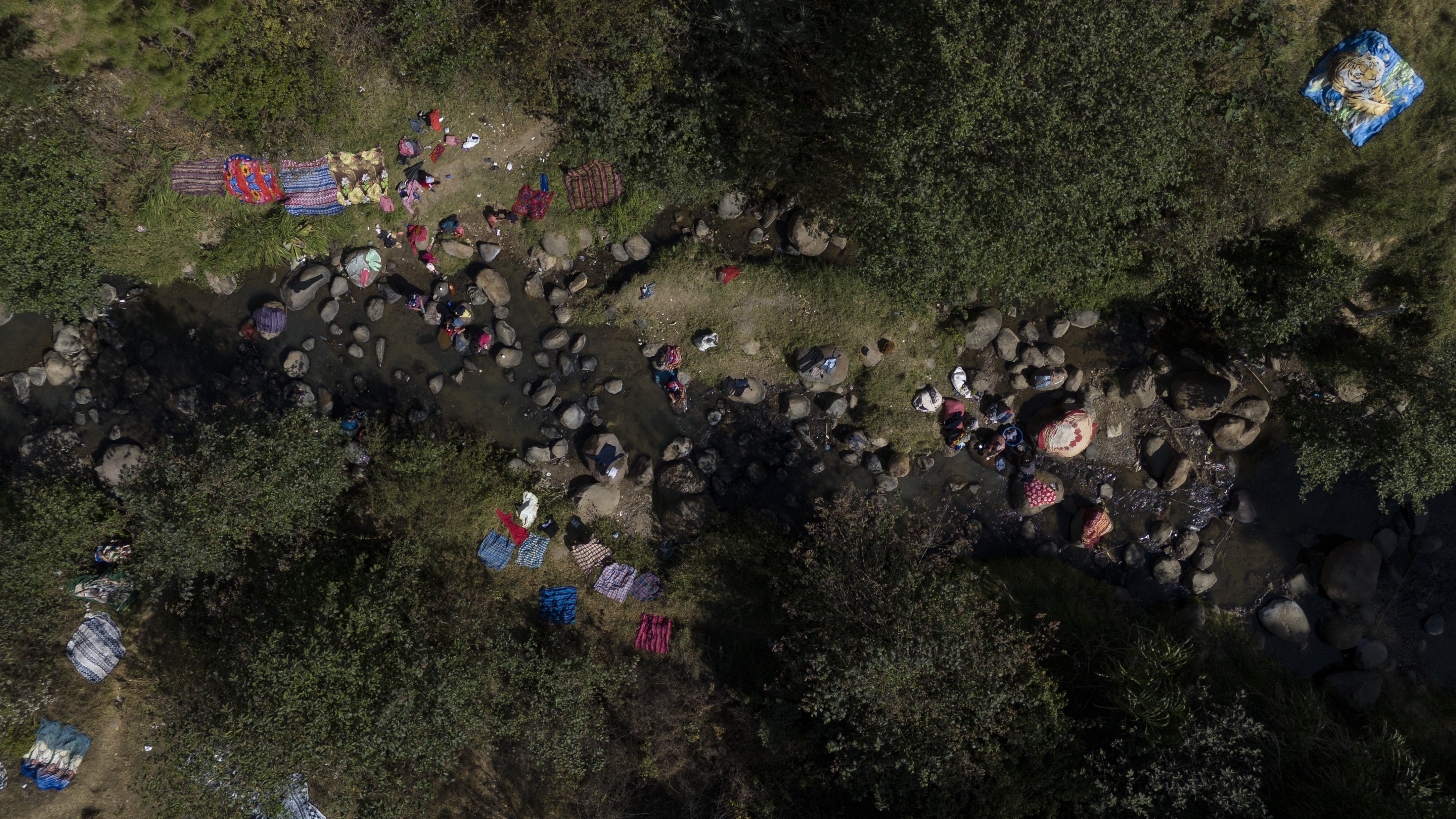An aerial view of a river in Santa María Chiquimula municipality, Totonicapán department, where people bathe and wash their clothes. 