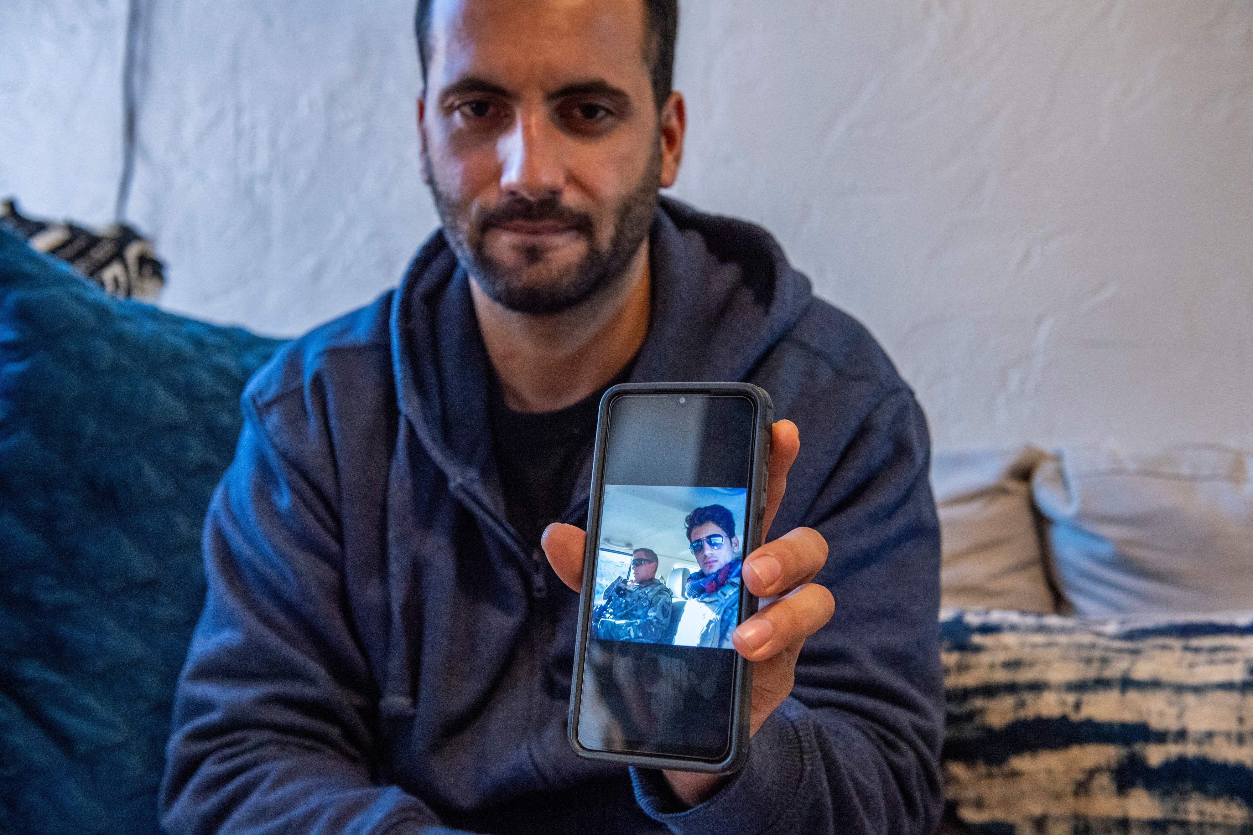 Afghani evacuee Israr, 26, shows photos on his phone of himself working in Afghanistan as a translator with military forces at his new apartment in Charlestown, Massachusetts, February 21, 2022.