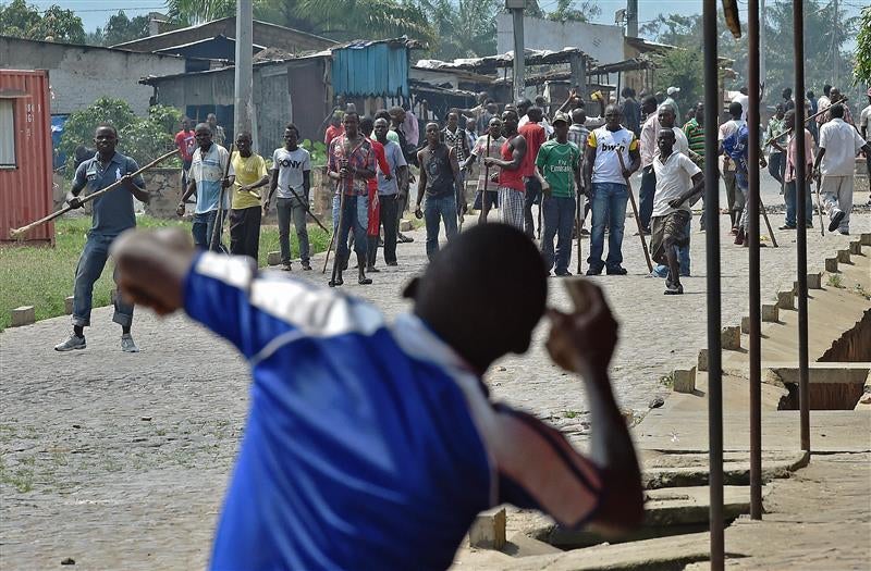 A protestor throwing rocks at members of Imbonerakure.