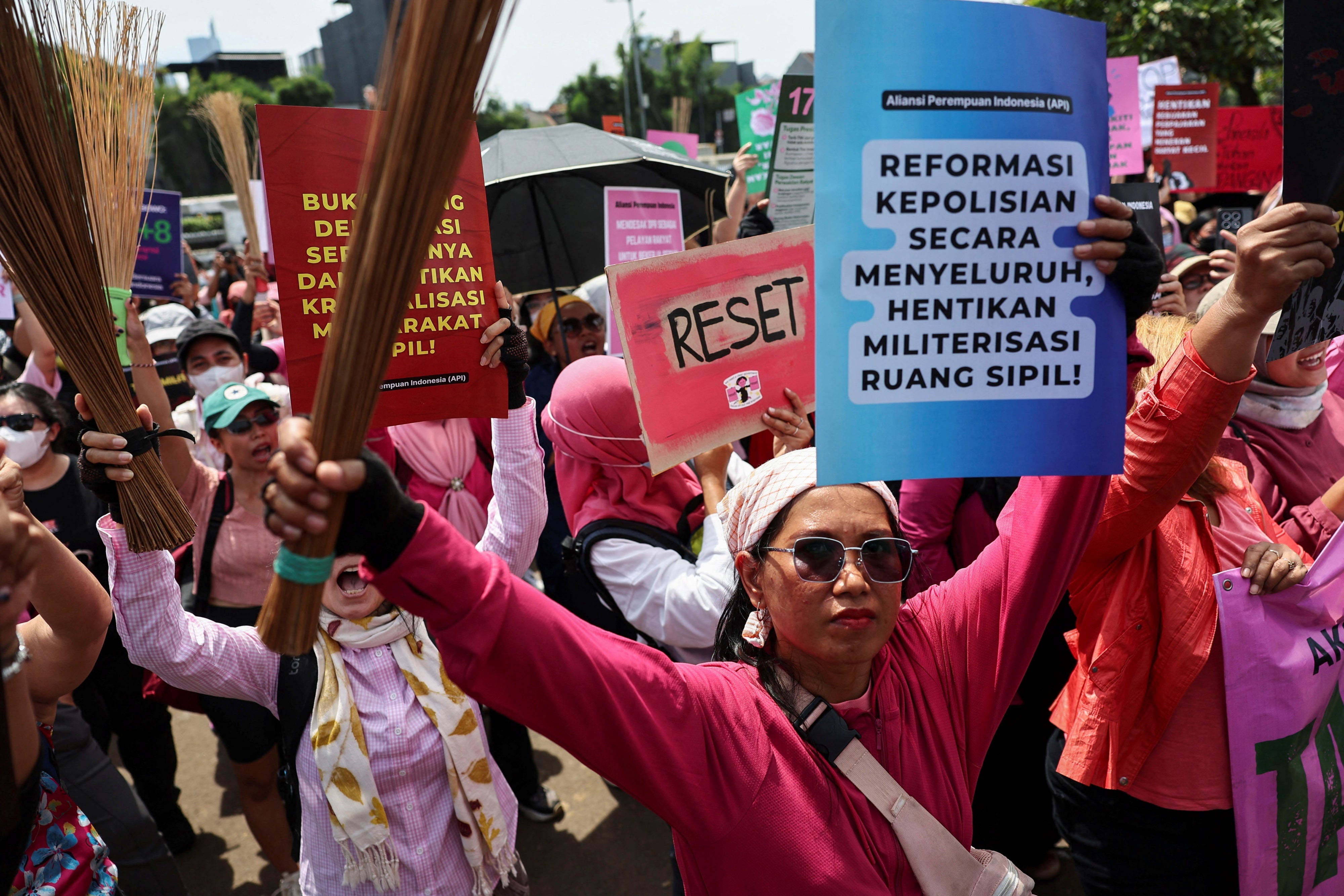 Protesters brandish brooms as a symbol of their calls for reform, and ending police brutality and lawmakers’ perks, outside the Indonesian parliament building in Jakarta, September 3, 2025. (