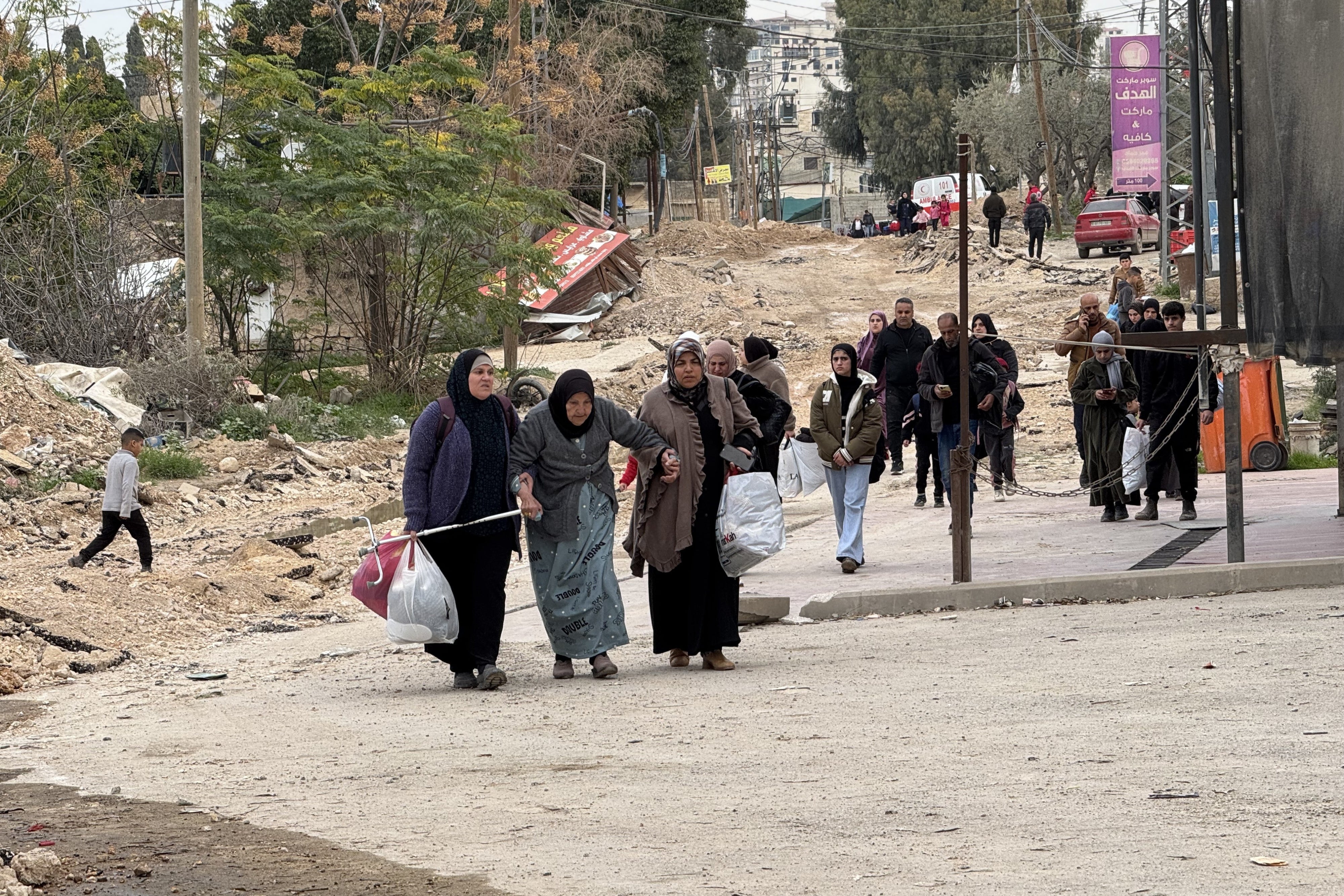 Palestinian families, including an older woman, are forcibly displaced from the Jenin refugee camp in the northern West Bank, walking along Balat al Shuhada road