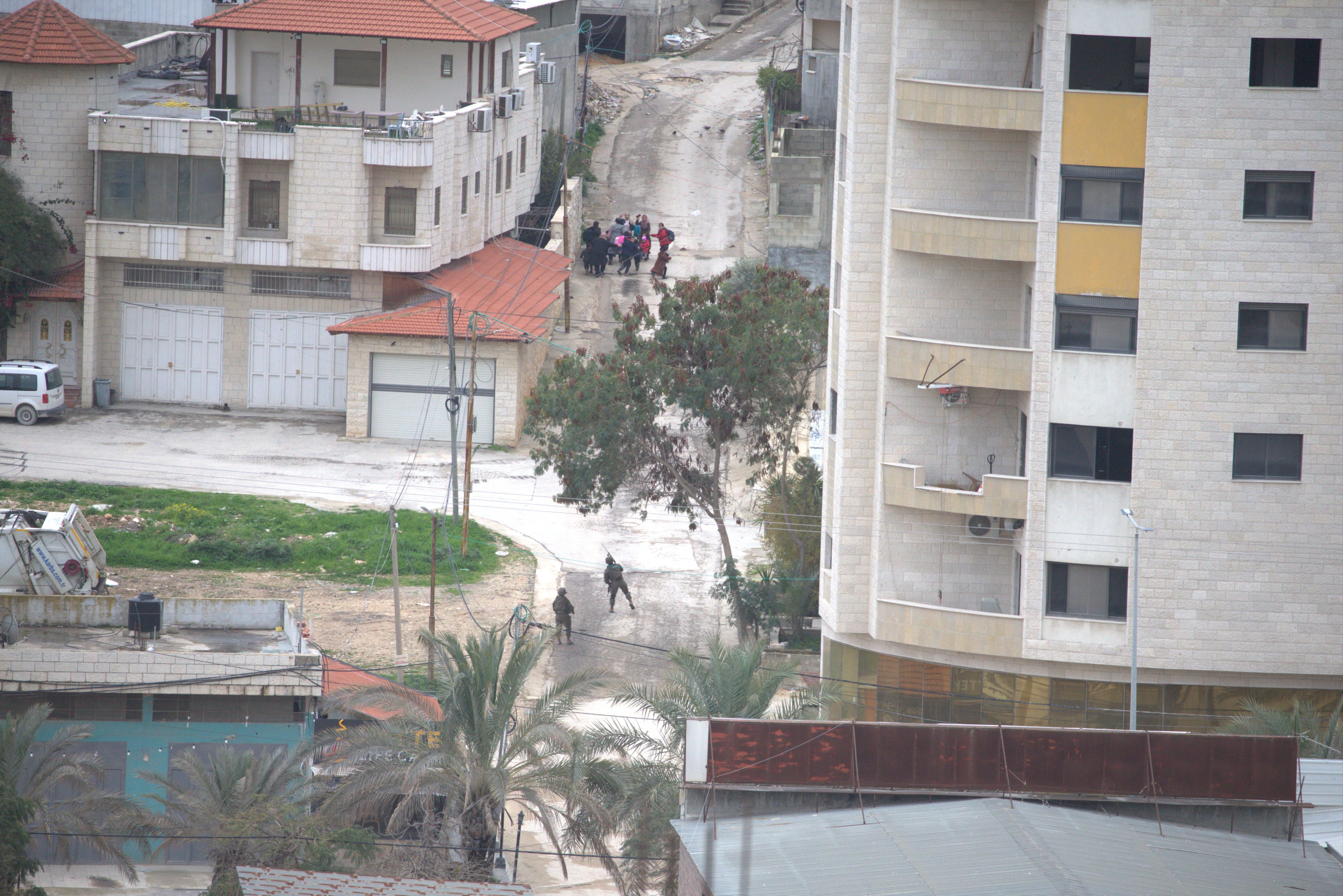 A group of women and children encounter two Israeli soldiers on the northwest edge of Nur Shams refugee camp in the northern West Bank, near Nablus Street, one of whom is seen with their weapon raised