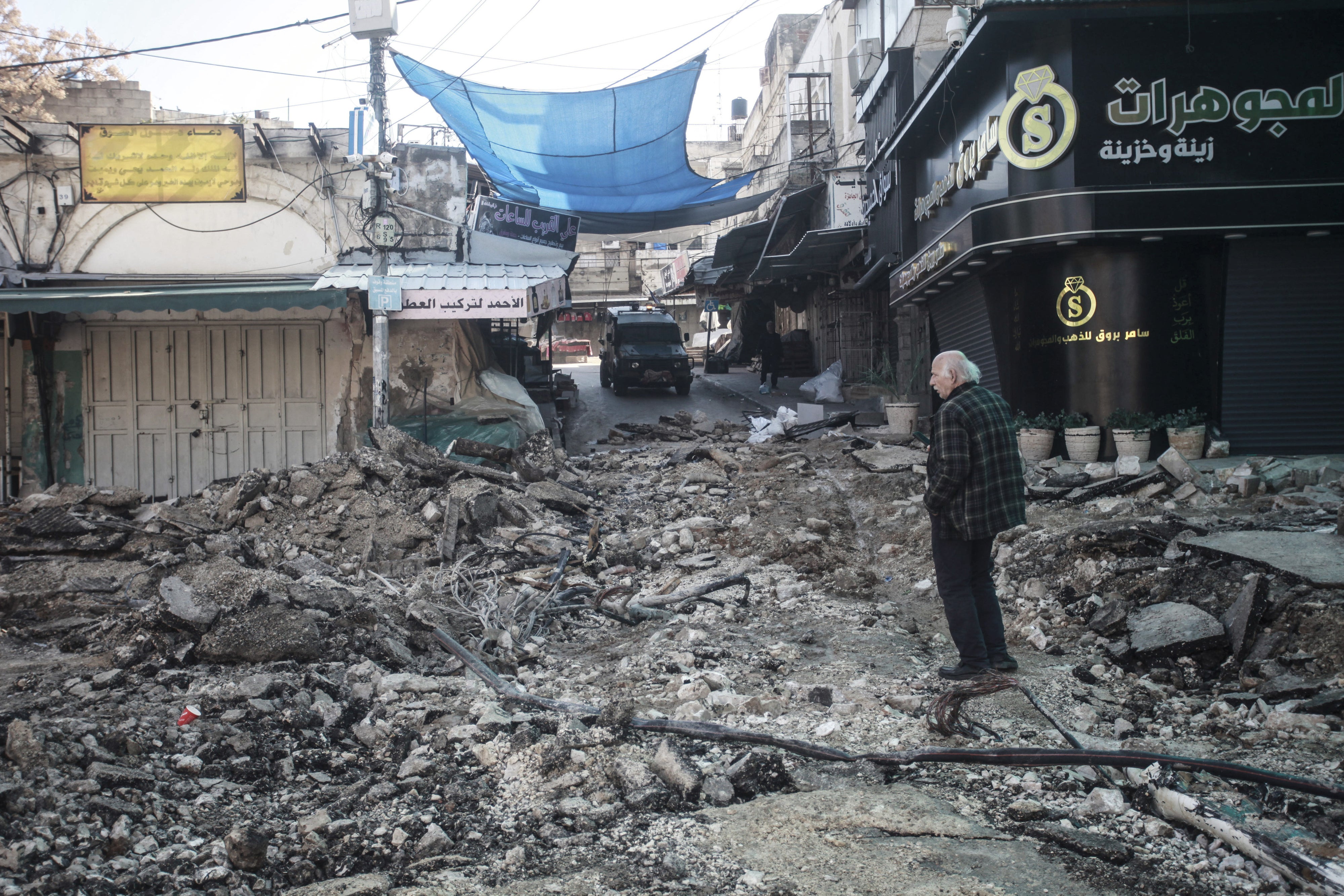An older Palestinian man stands in the middle of a destroyed market in Tulkarem