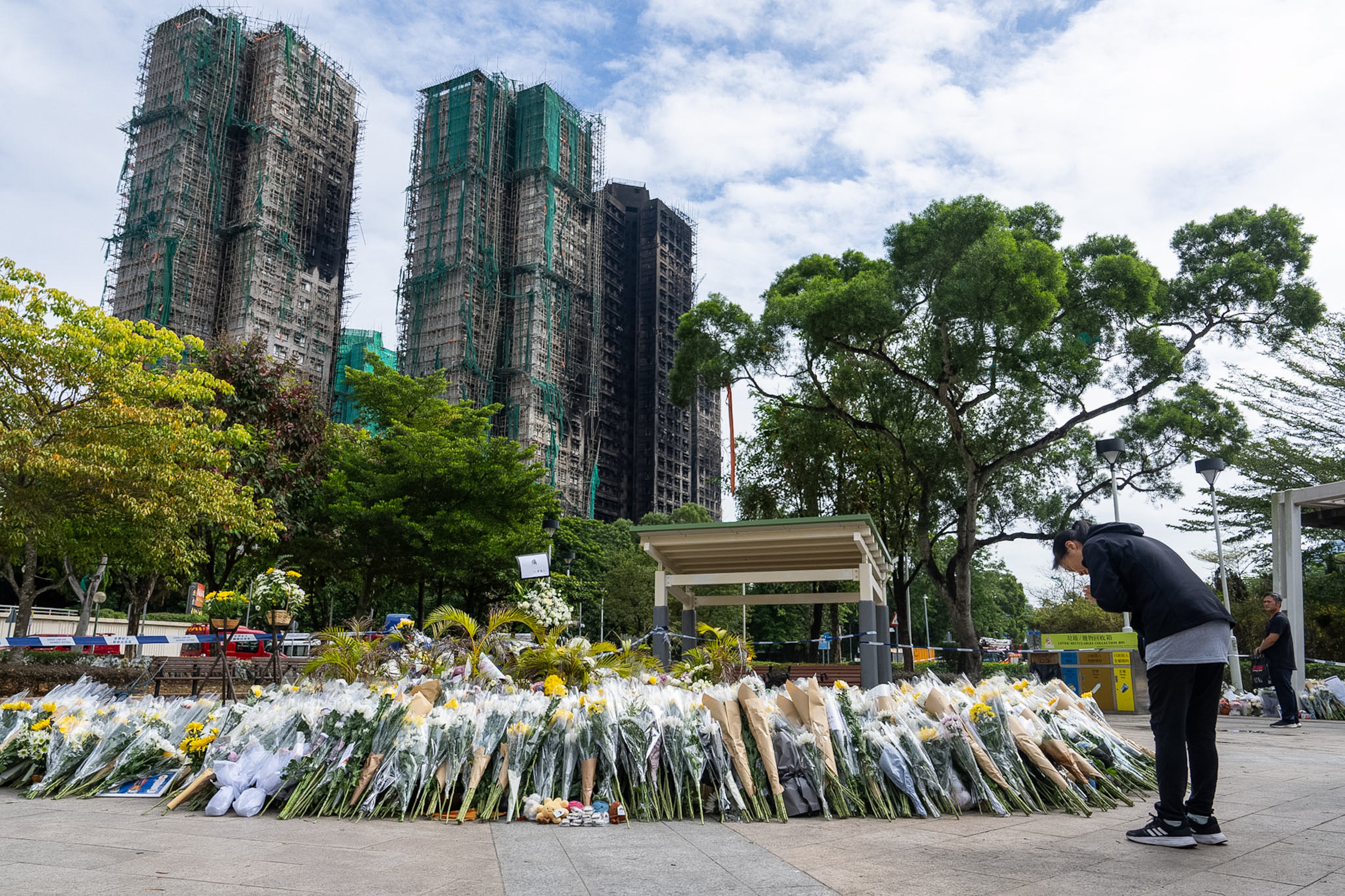 Flower offering in front of burnt buildings, woman praying