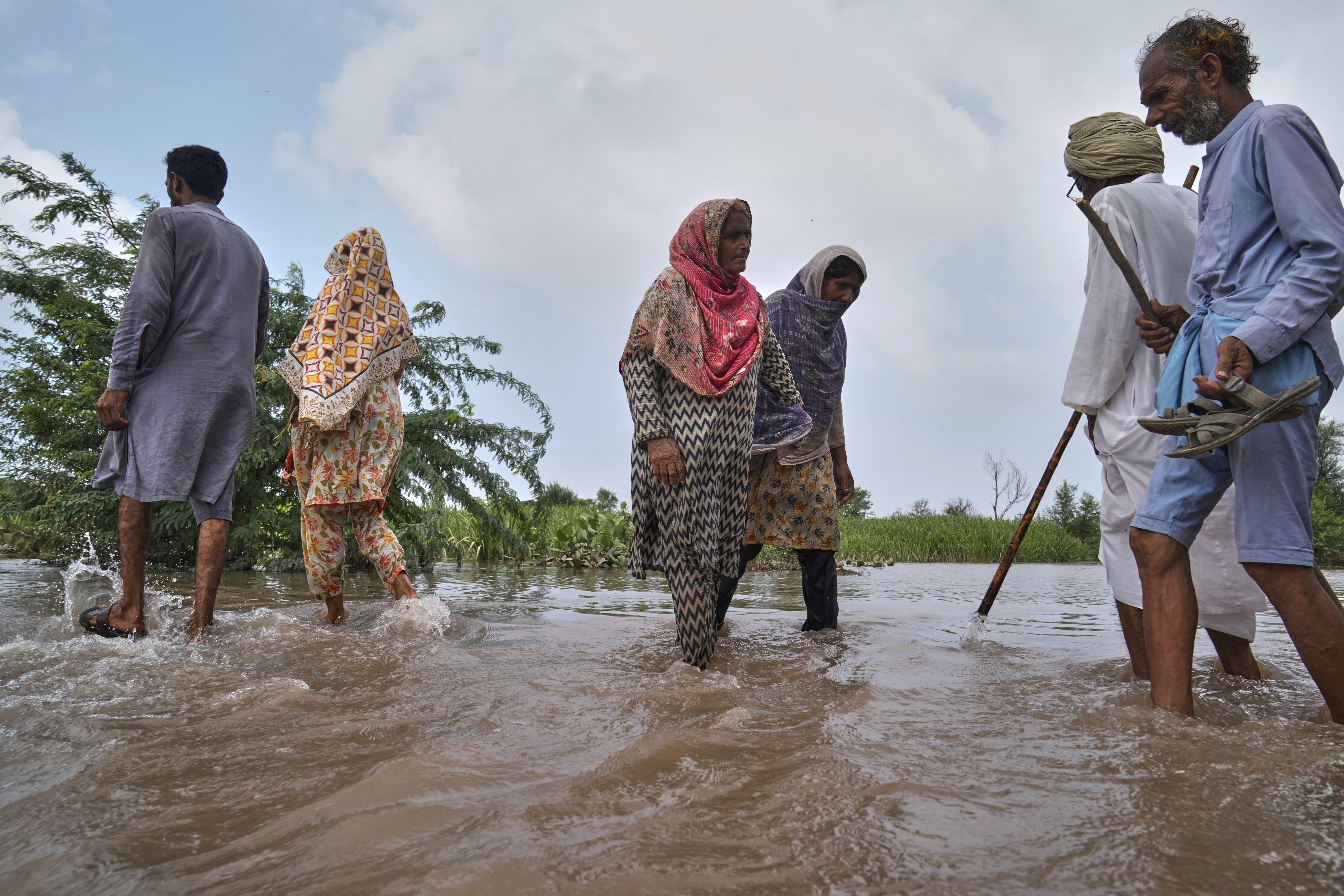 Villagers wade through a flooded area.