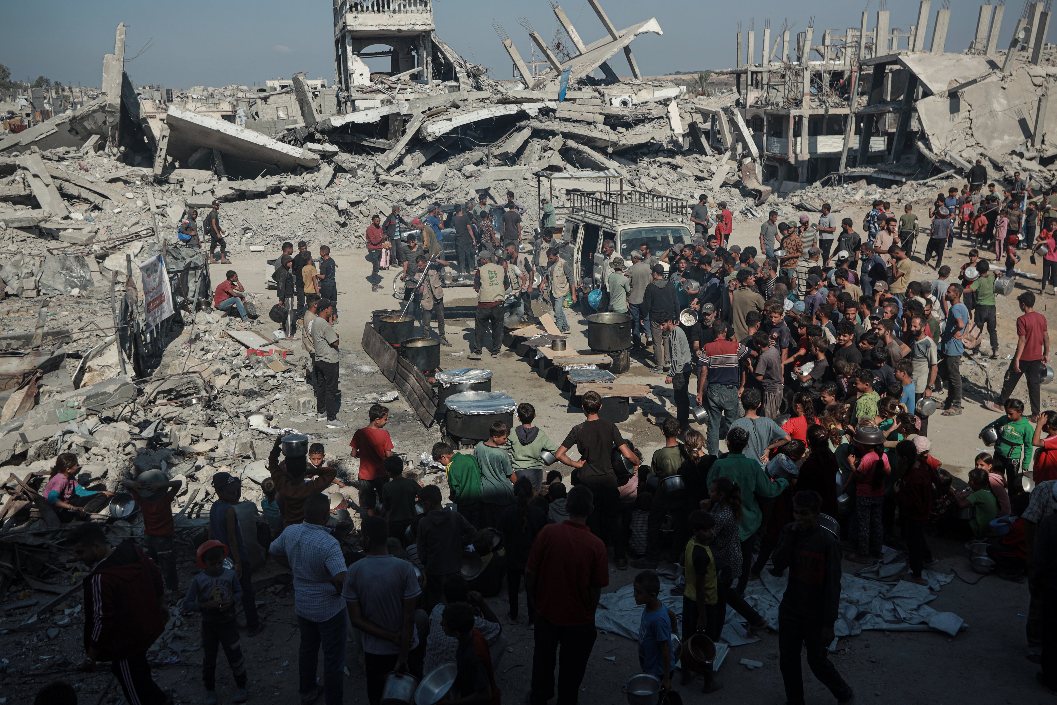 Palestinians flock to the area where a charitable organization distributes hot food as food crisis persists in Beit Lahia, Gaza on October 28, 2025. 