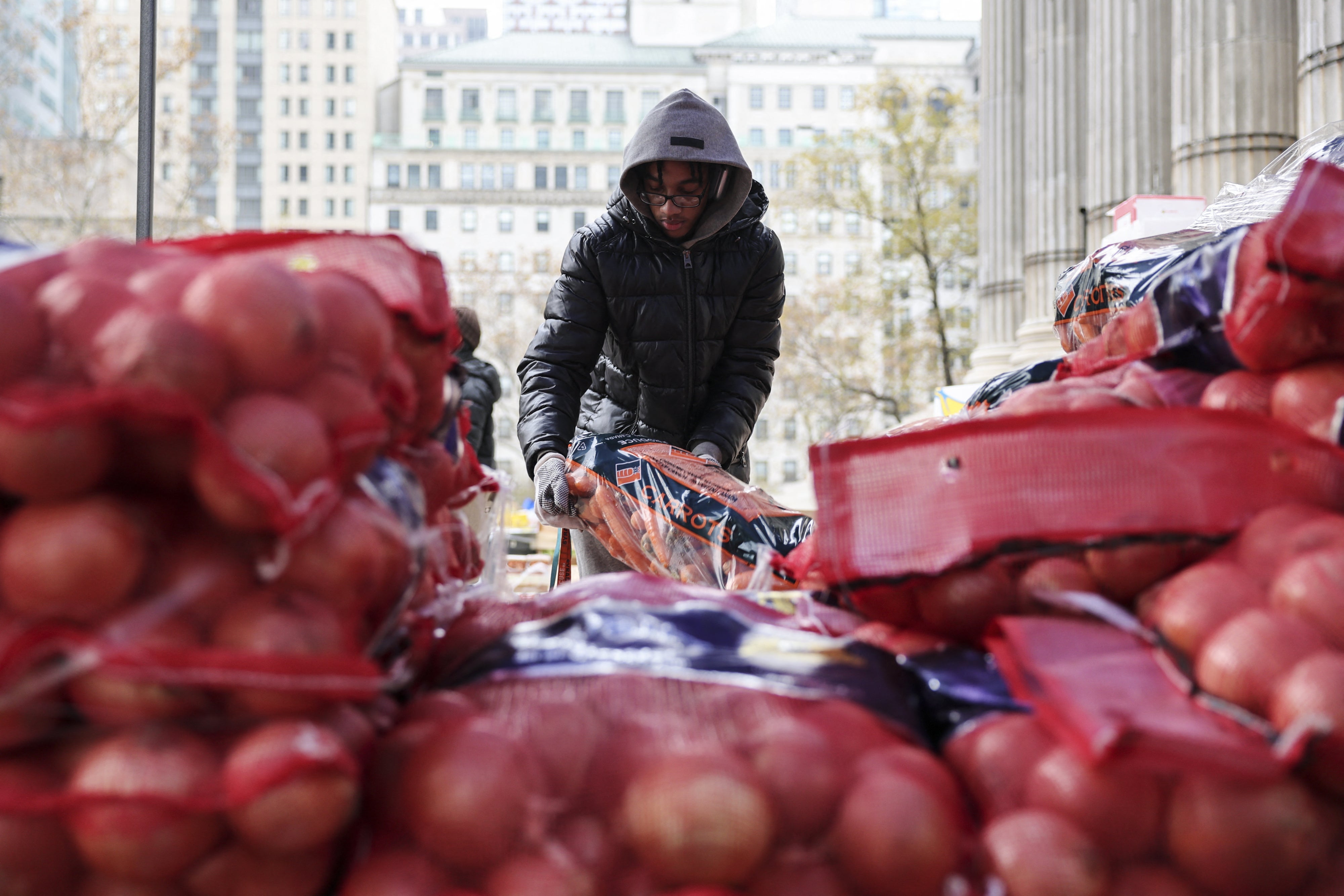 Un bénévole plaçait des sacs de fruits et légumes sur un site de distribution de nourriture pour des personnes indigentes devant Brooklyn Borough Hall, la mairie de ce quartier de New York, le 21 novembre 2025. 