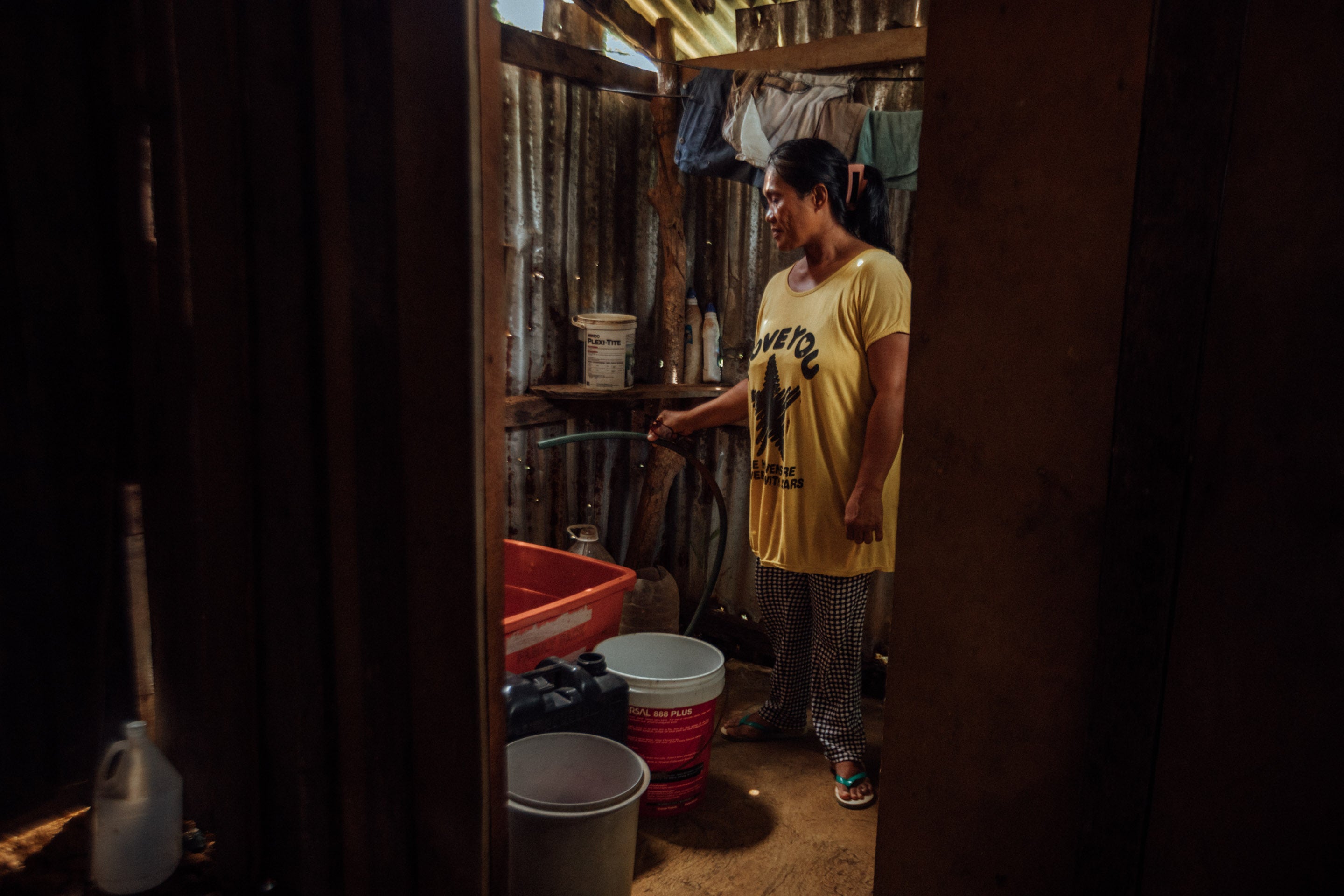 Zenaida attempts to get water in her home where access is sporadic, in Siargao, Philippines, September 2025. © 2025 Camille Robiou du Pont/Human Rights Watch   