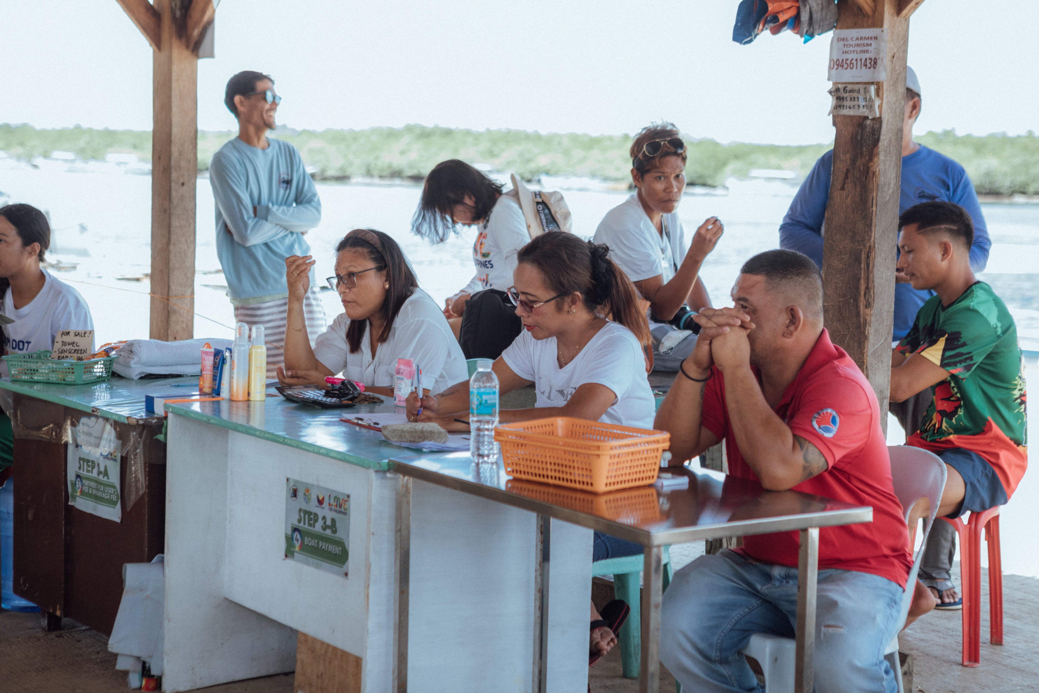 Mirasol E. Escanan (C) at work as the port treasurer for the tourism sector in Del Carmen, Siargao, Philippines, 2025.