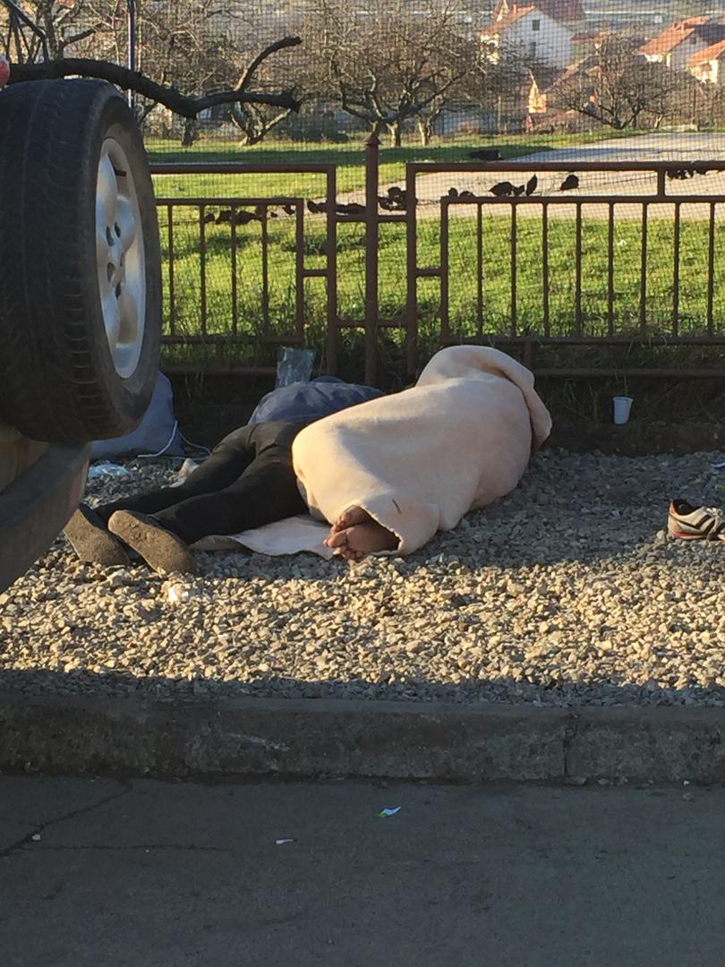 Two Afghan asylum seekers sleeping on the ground outside a registration camp in Dimitrovgrad, Serbia.
