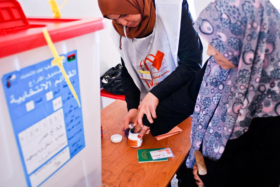A female election worker helps an elderly voter at a polling station in Benghazi.