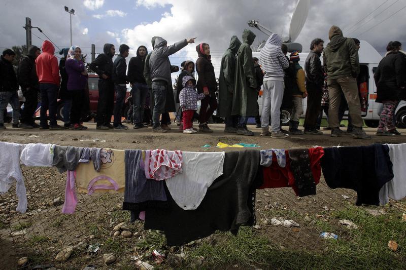 Refugees and migrants line up to receive aid in a makeshift camp at the Greek-Macedonian border, near the Greek village of Idomeni March 4, 2016. 