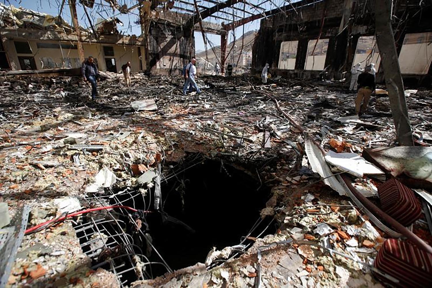 صحفيون ورجال شرطة يعاينون مكان الحادث في الصالة الكبرى في صنعاء حيث هاجمت طائرات التحالف بقيادة السعودية مراسم عزاء في 8 أكتوبر/تشرين الأول 2016. 